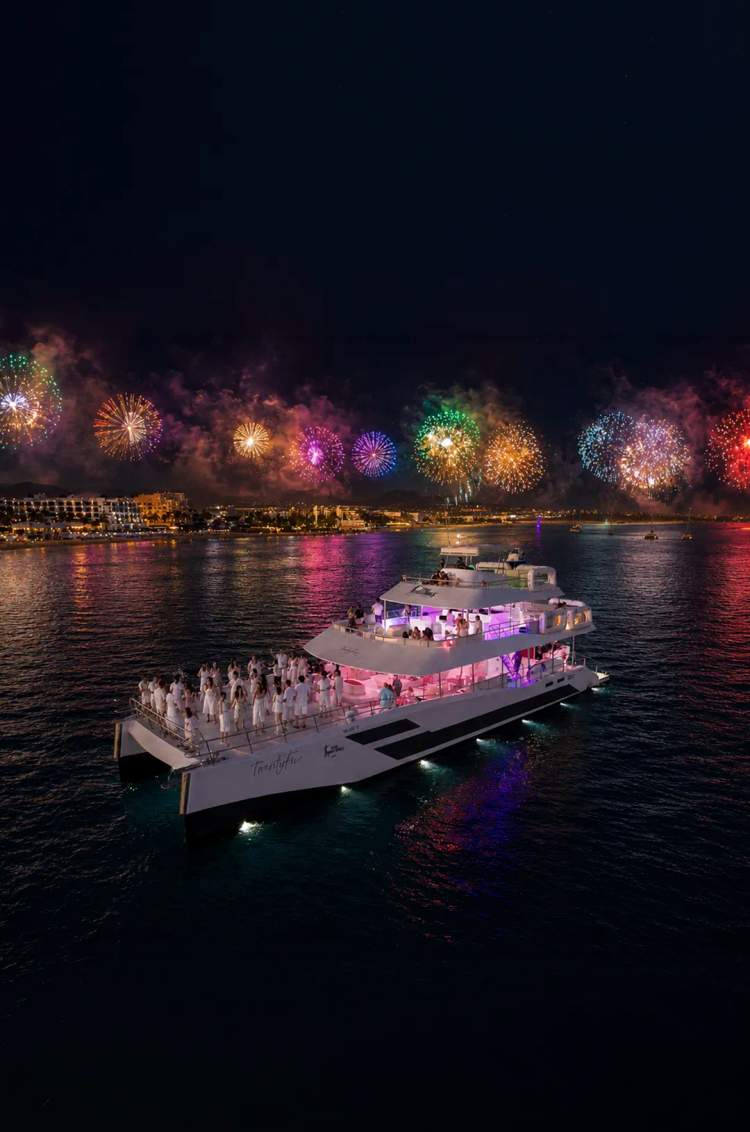 New Years catamaran Golden Mignight with guests in white enjoying fireworks over the ocean with Cabo Adventures
