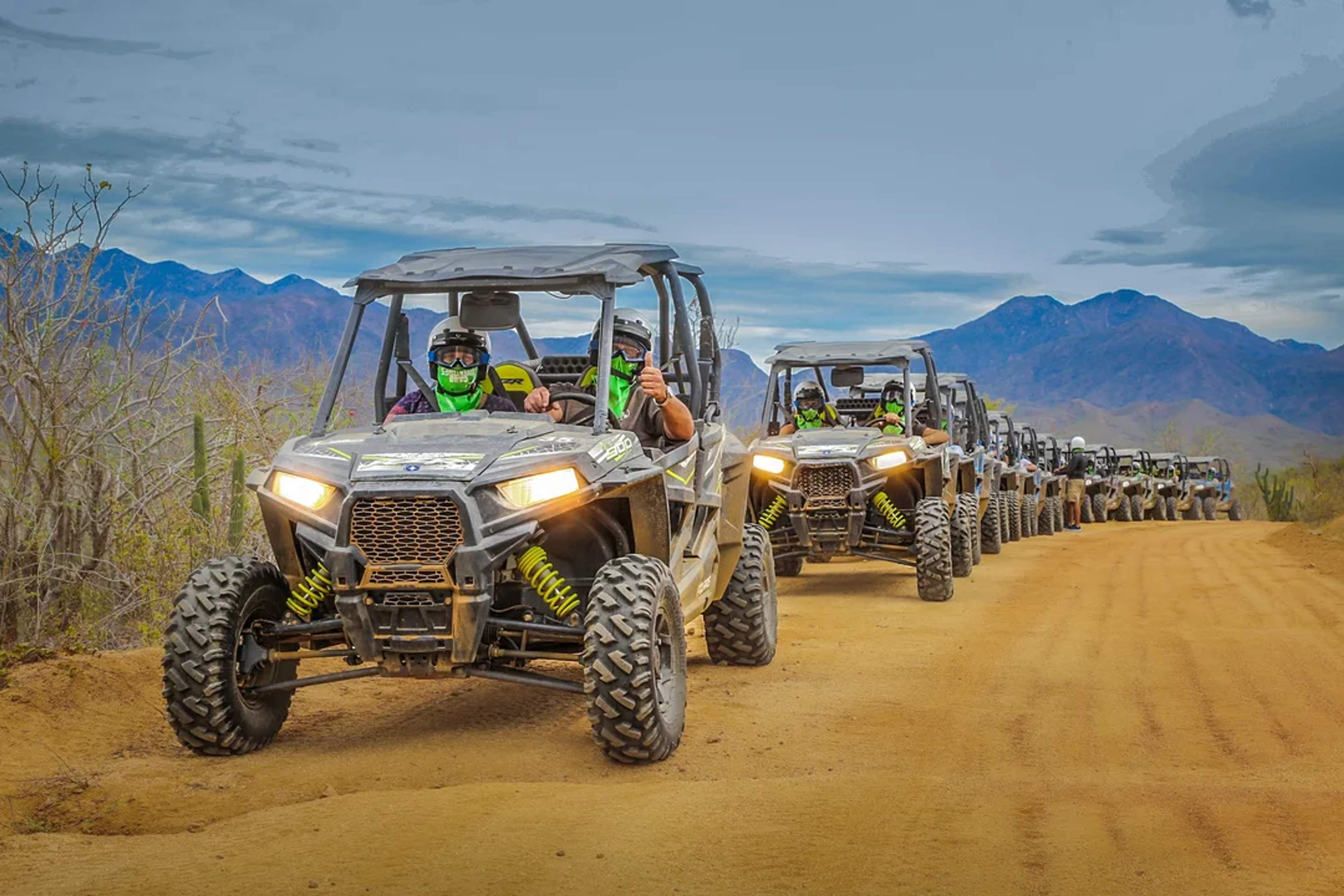 Un grupo de UTVs recorre senderos áridos del desierto, rodeado de montañas, cactus y aventura en Cabo San Lucas.