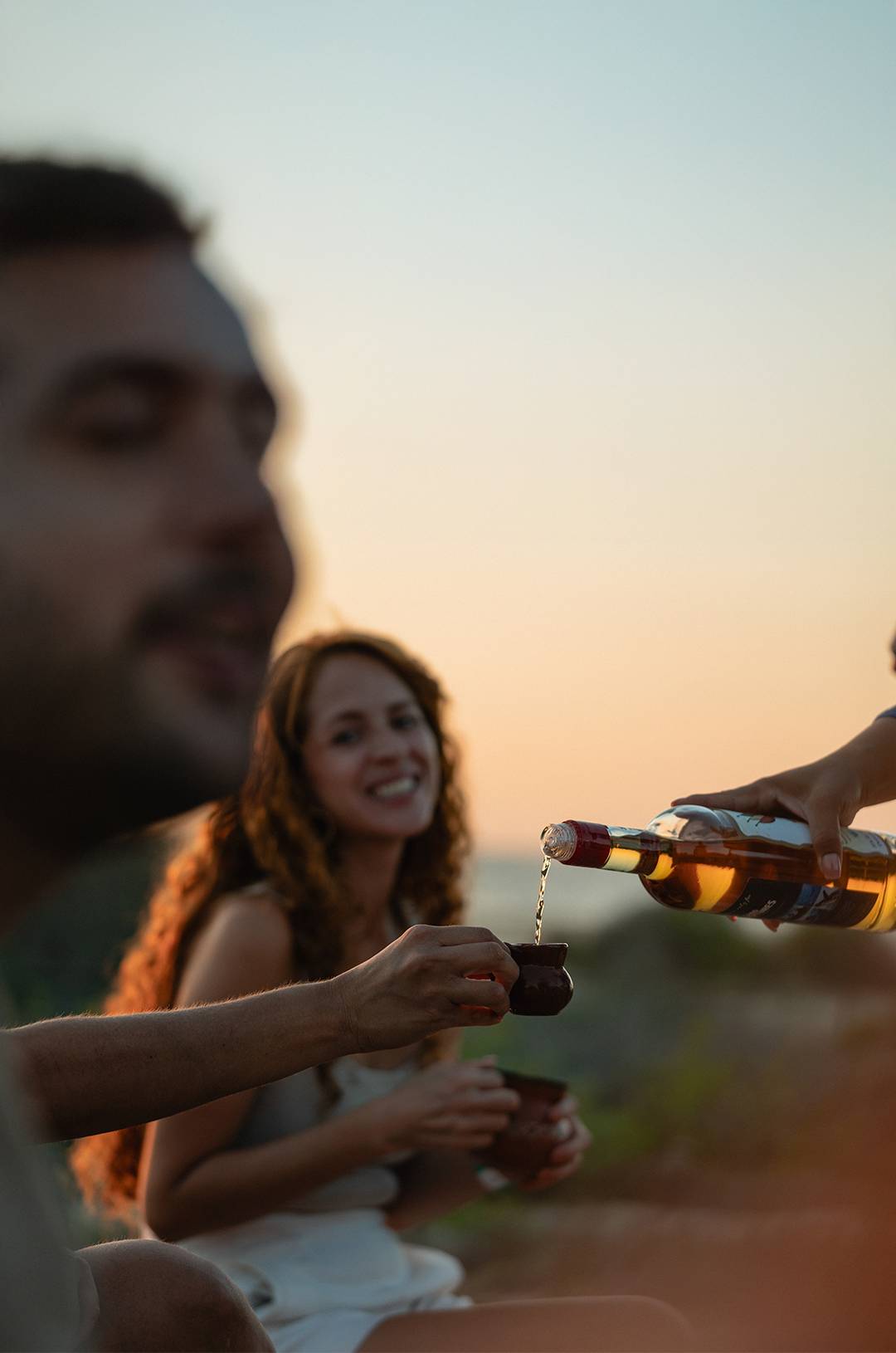 Couple enjoying cocktails served by bartender at Tierra Sagrada Beach Club bar in Cabo San Luca