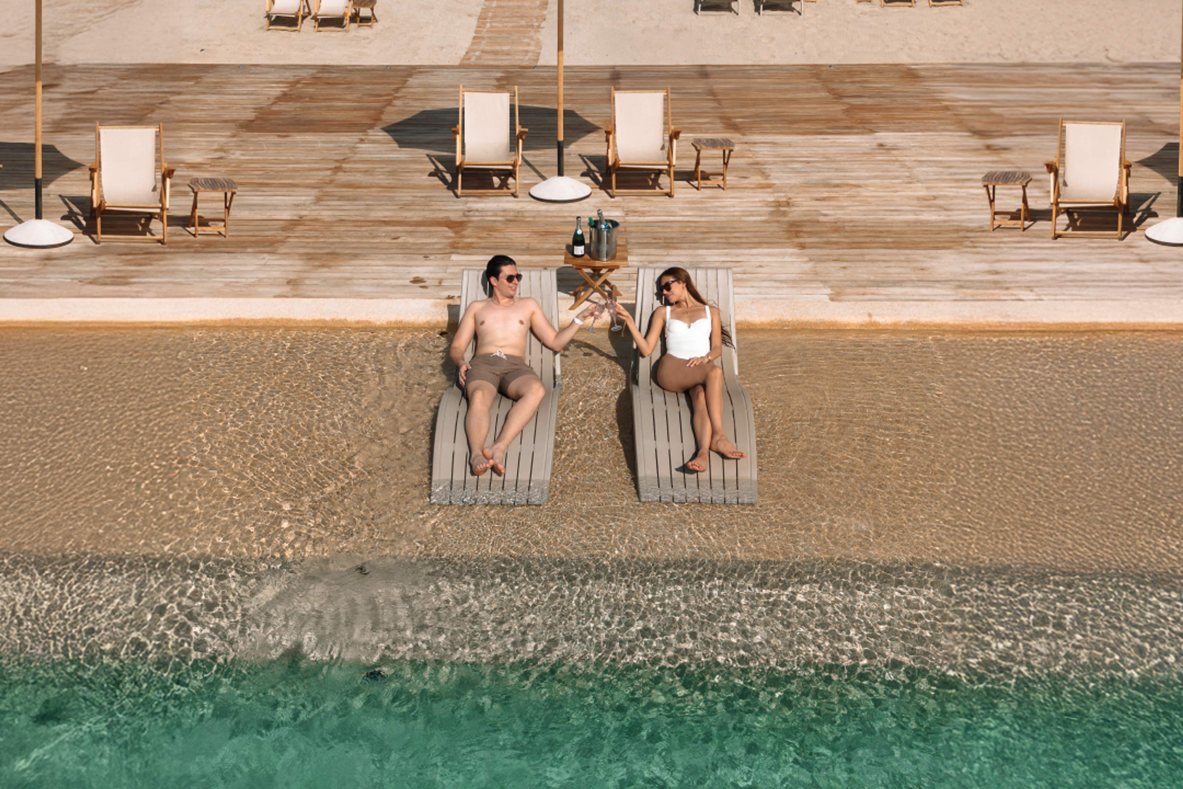 Couple toasting champagne on loungers in infinity pool at Tierra Sagrada, Instagram spot in Cabo