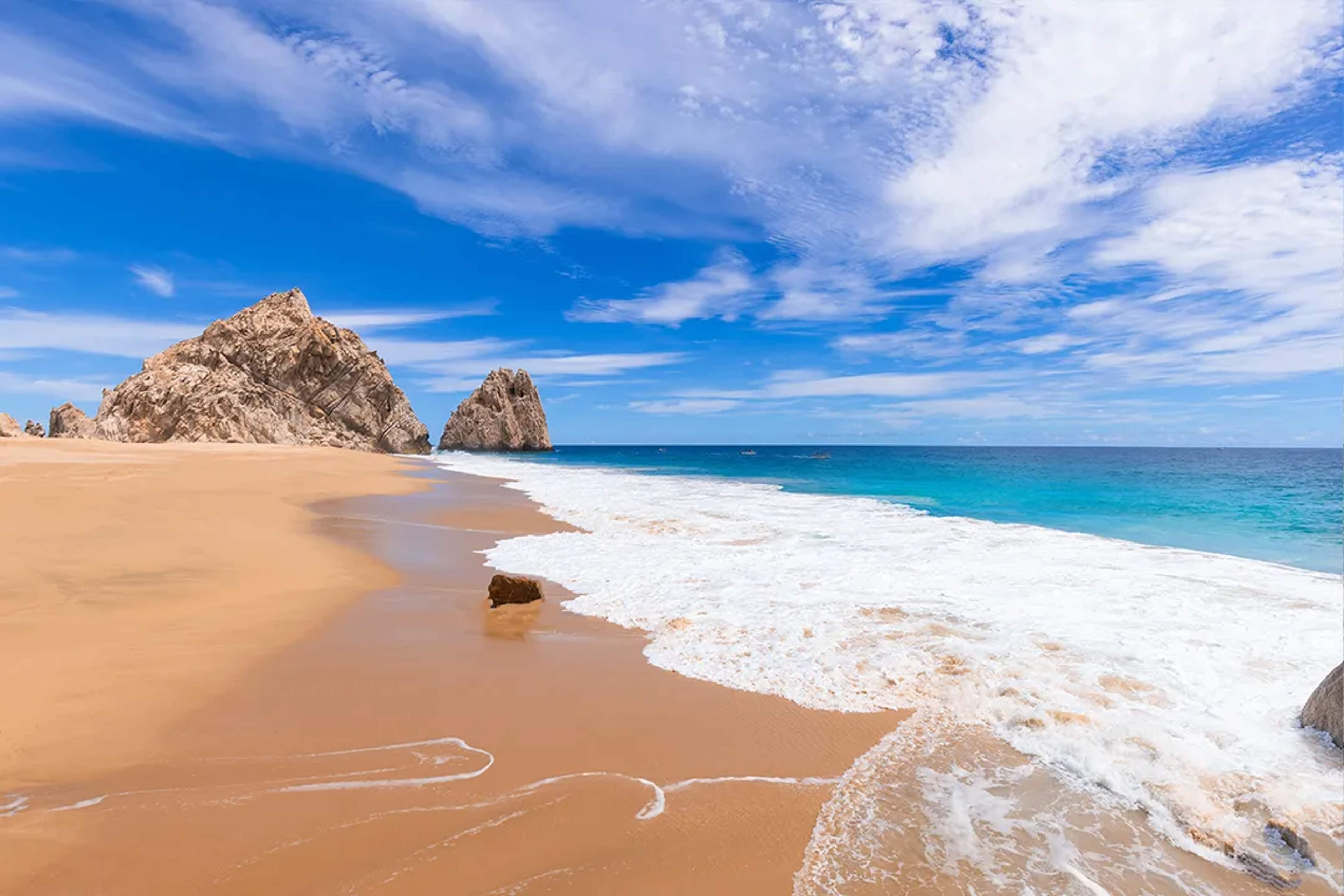 Divorce Beach in Cabo San Lucas with golden sand, turquoise waves and dramatic rock formations by the Pacific!