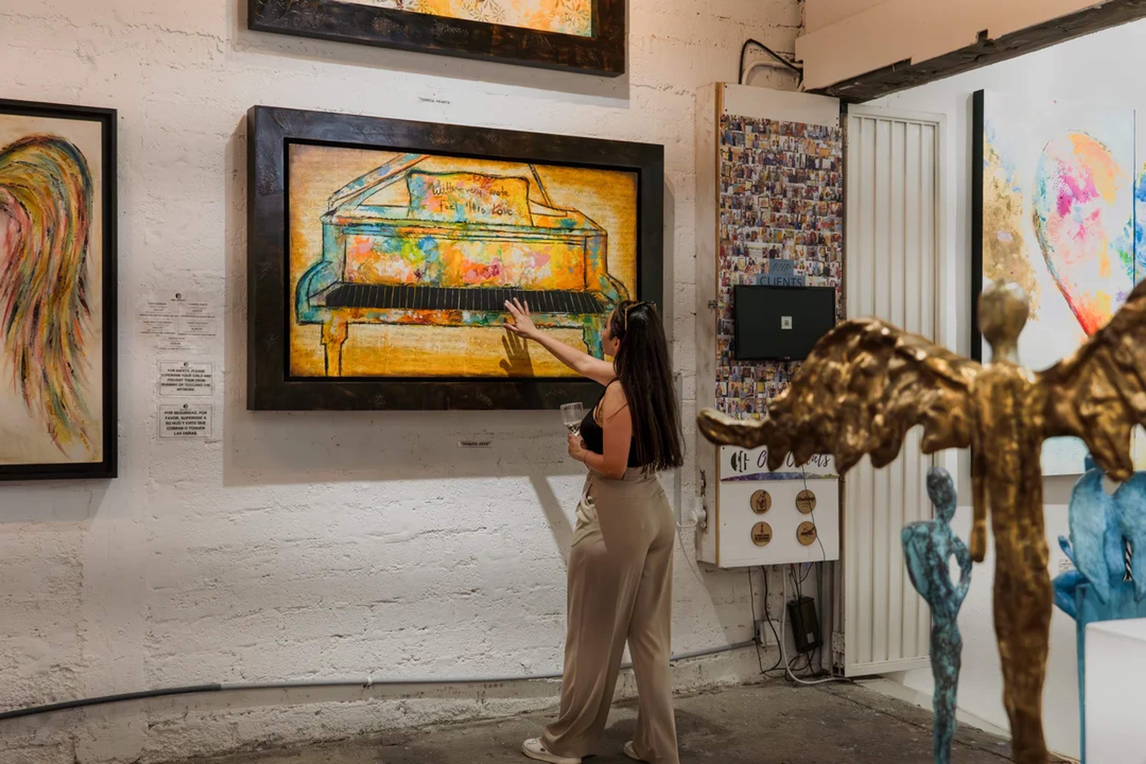 Mujer admira un piano colorido en galería de arte durante el Art Walk en San José del Cabo.