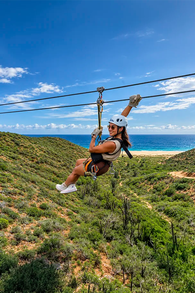 Mujer en tirolesa con vistas al mar en Pacific Zipline Adventure de Cabo Adventures.