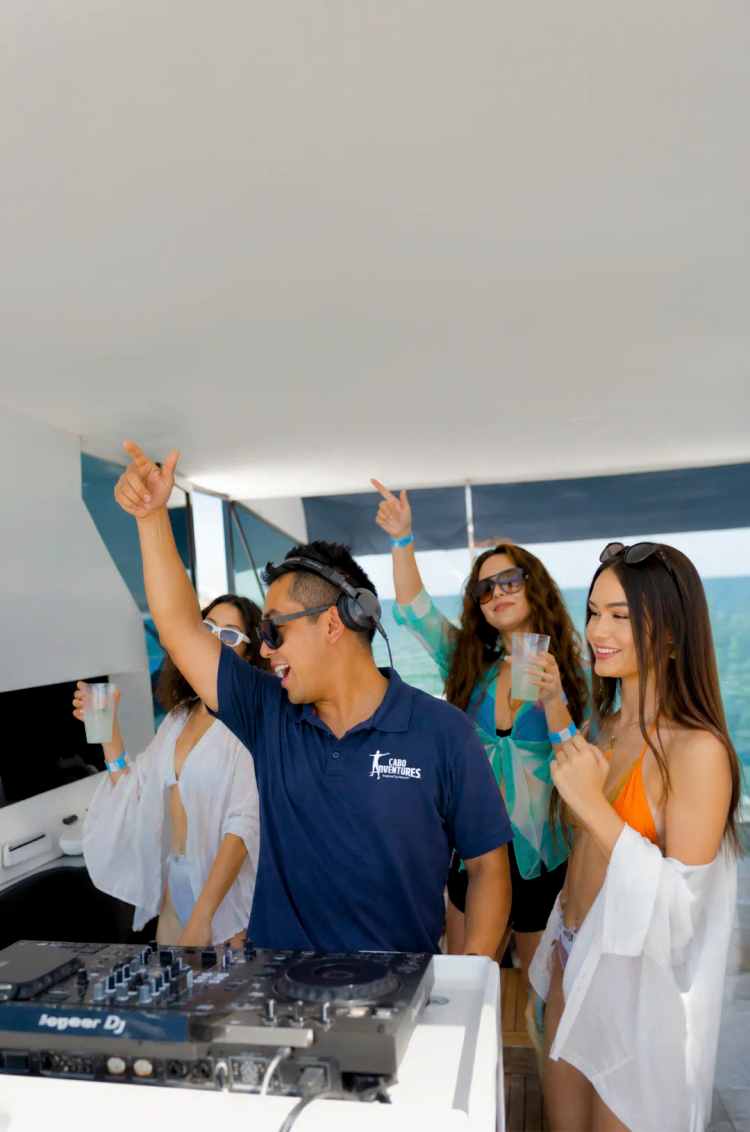 Amigos disfrutando un paseo en catamarán en Cabo con bebidas, vistas al mar y ambiente social a bordo