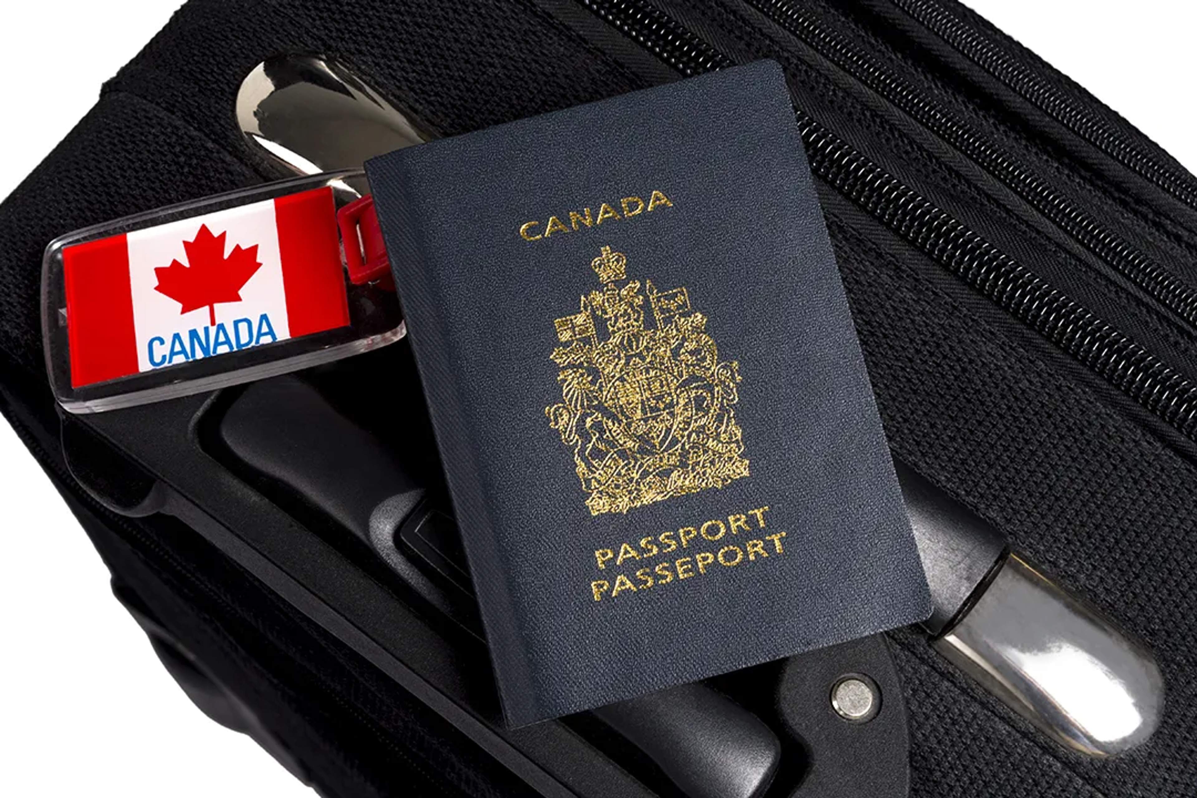 Pasaporte canadiense sobre una maleta negra con una etiqueta de equipaje con la bandera de Canadá.