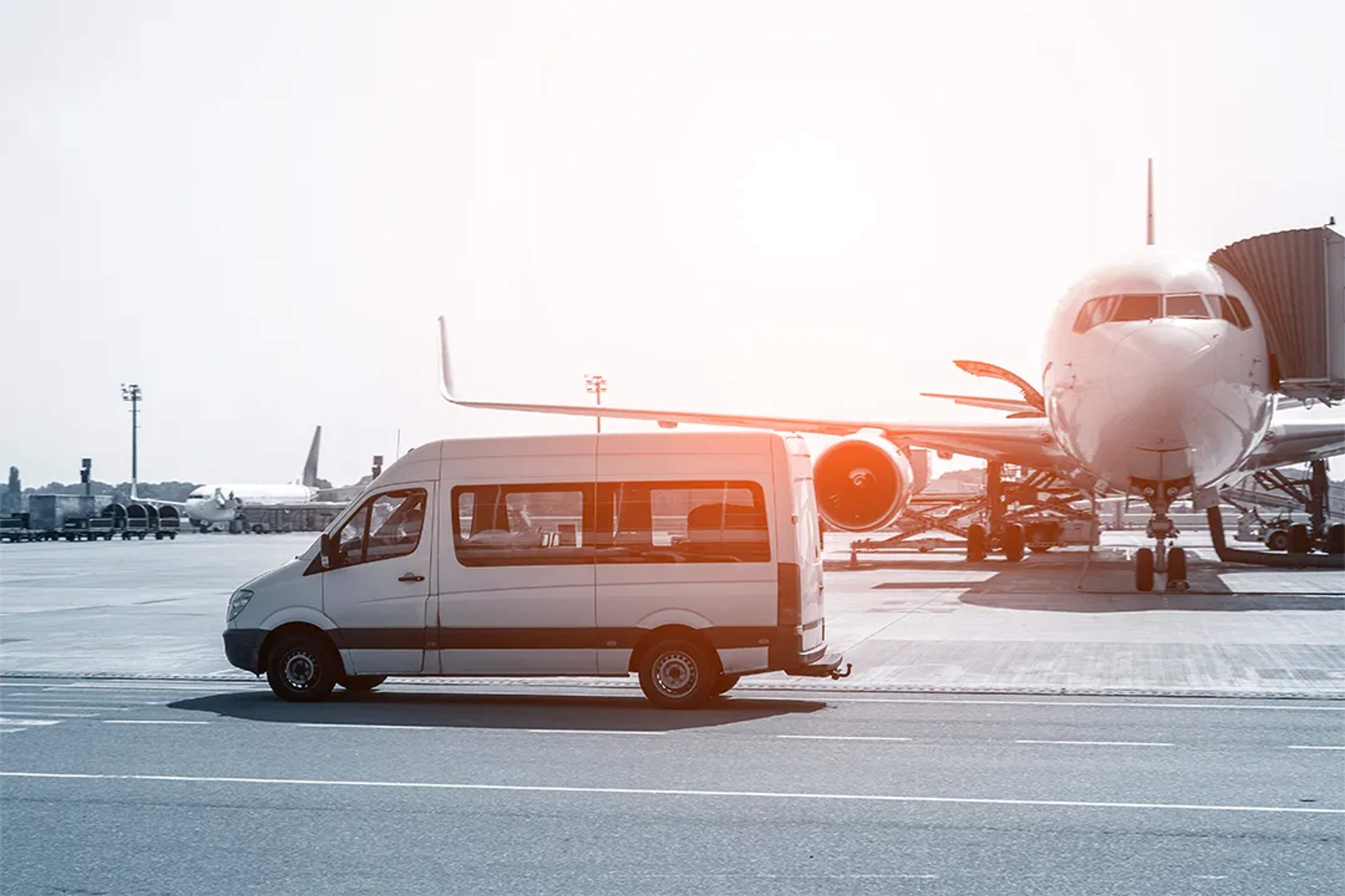 Shuttle van in front of a plane at the airport during sunrise.