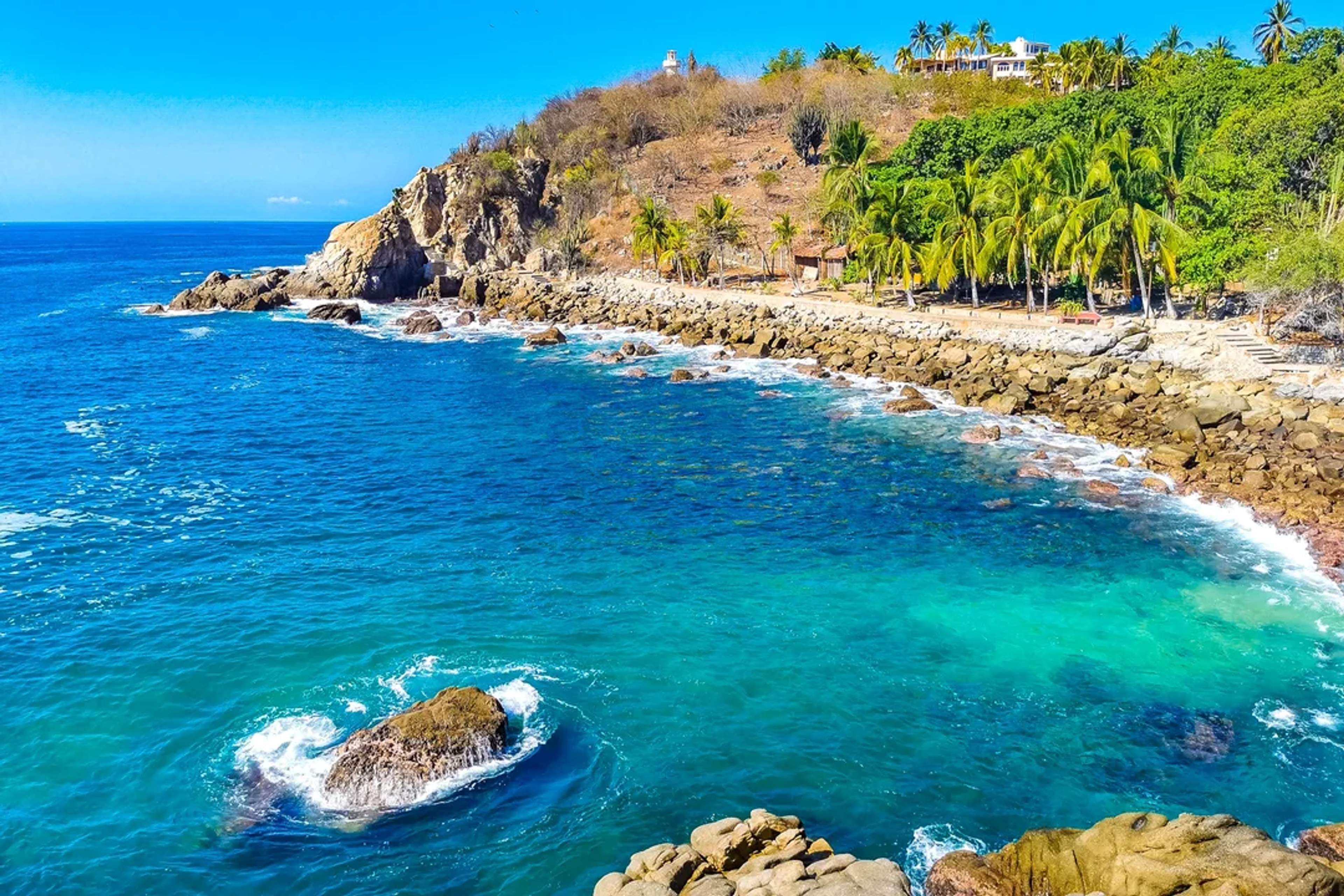 Rocky coast with turquoise sea and palm trees, perfect for exploring and sunbathing.