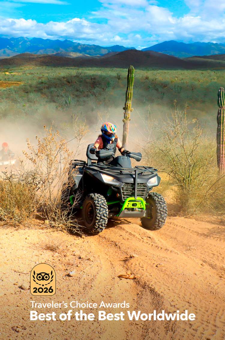 Conductor de ATV en un sendero polvoriento del desierto rodeado de cactus, montañas al fondo y insignia de Travelers' Choice.