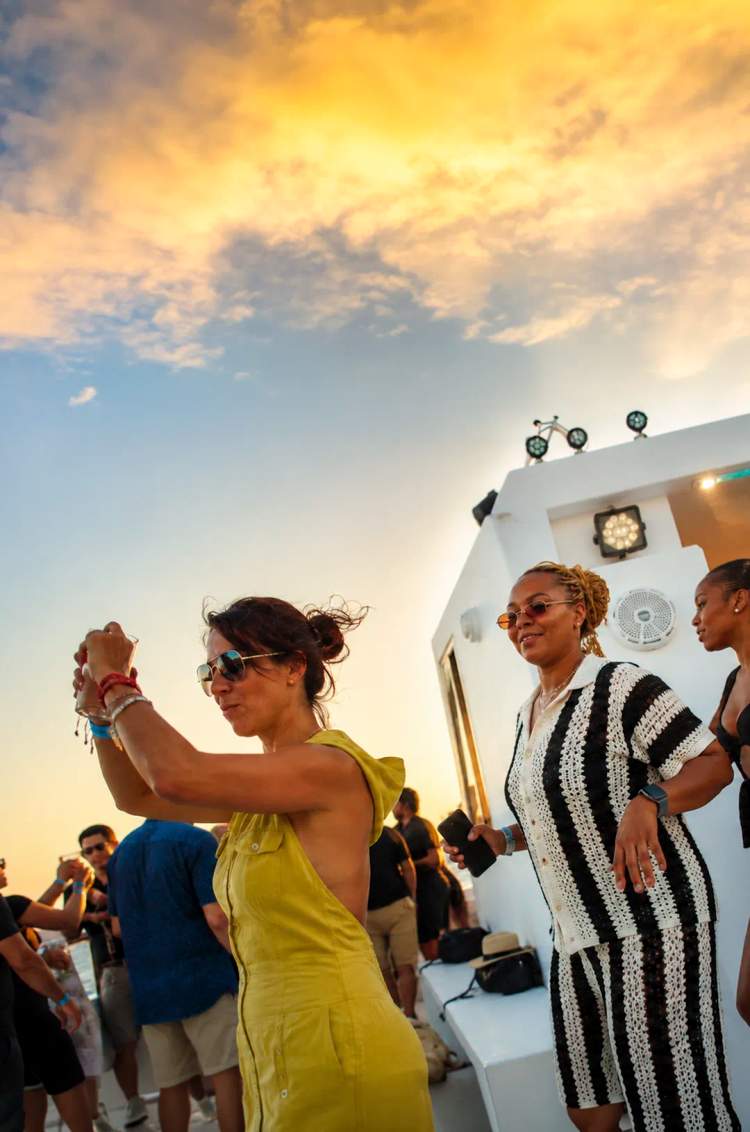 Guests dancing and enjoying a sunset party aboard the Oceanus catamaran in Los Cabos.