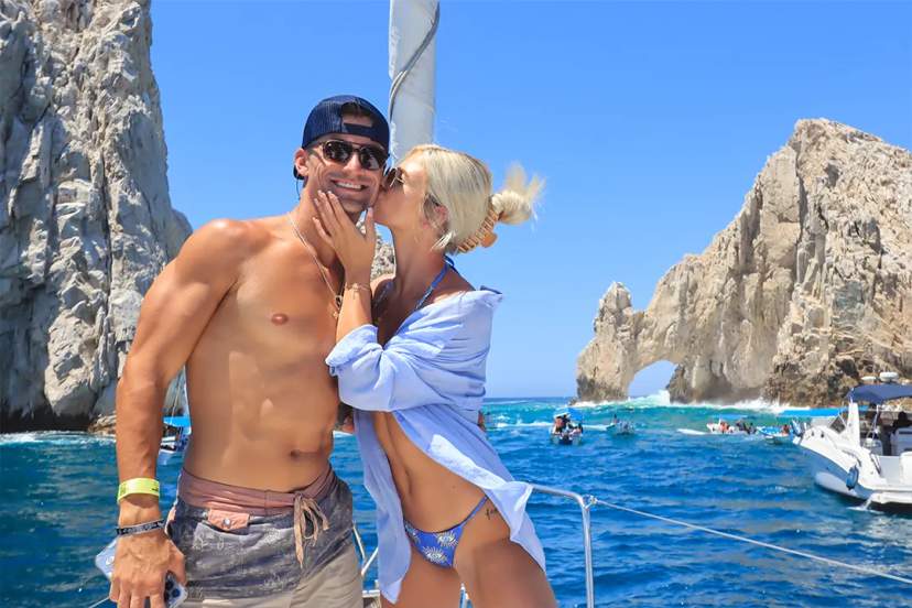Couple enjoying a romantic moment on a catamaran at El Arco, Cabo San Lucas, with turquoise sea and iconic rock arch