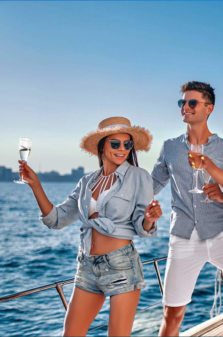 Grupo de amigos celebrando con bebidas en un velero bajo el sol, disfrutando de un día divertido en el mar.