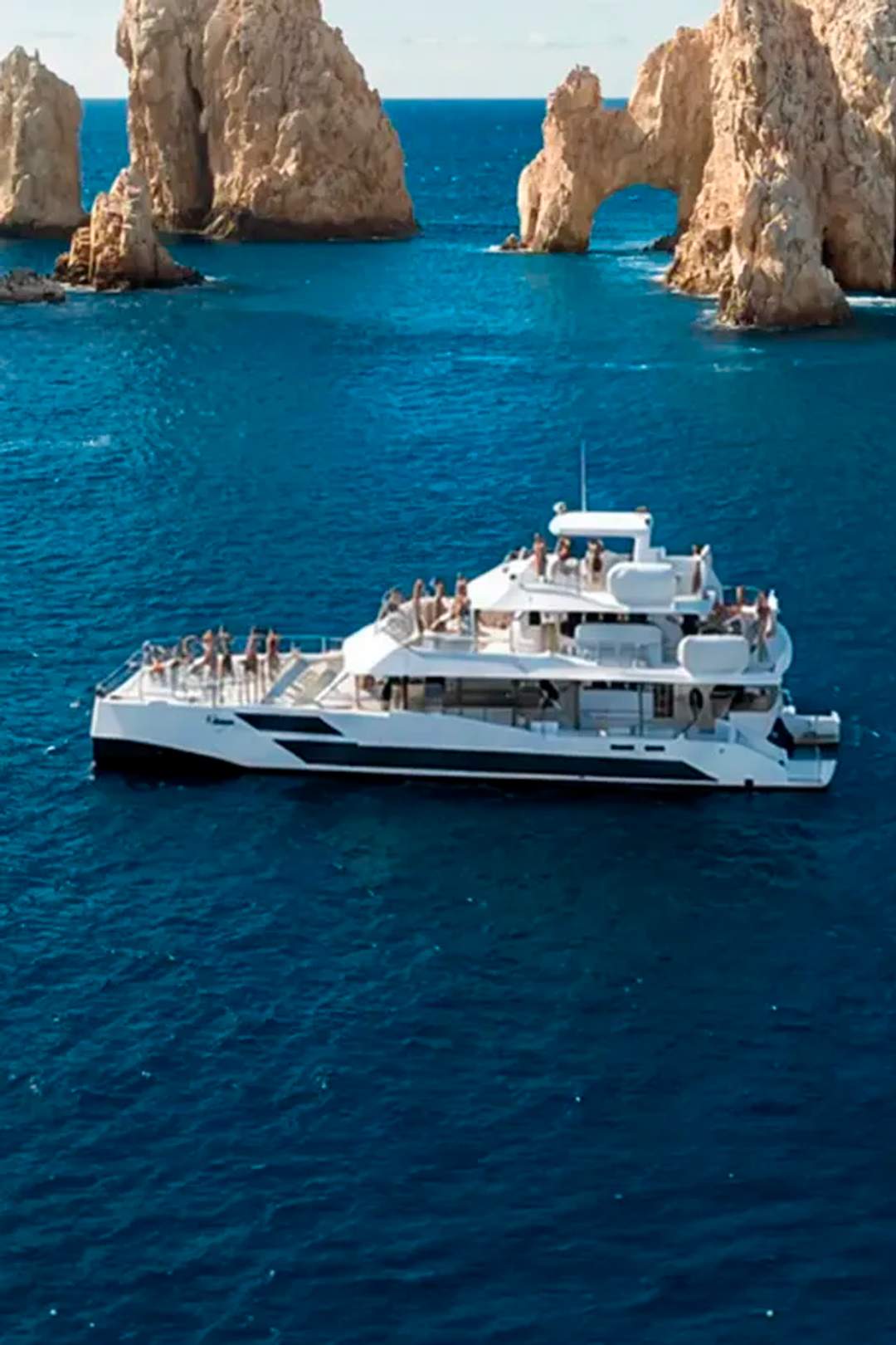 TwentyFive premium 100-ft catamaran sailing in Cabo San Lucas, triple-deck design, open sea views and luxury day cruise.