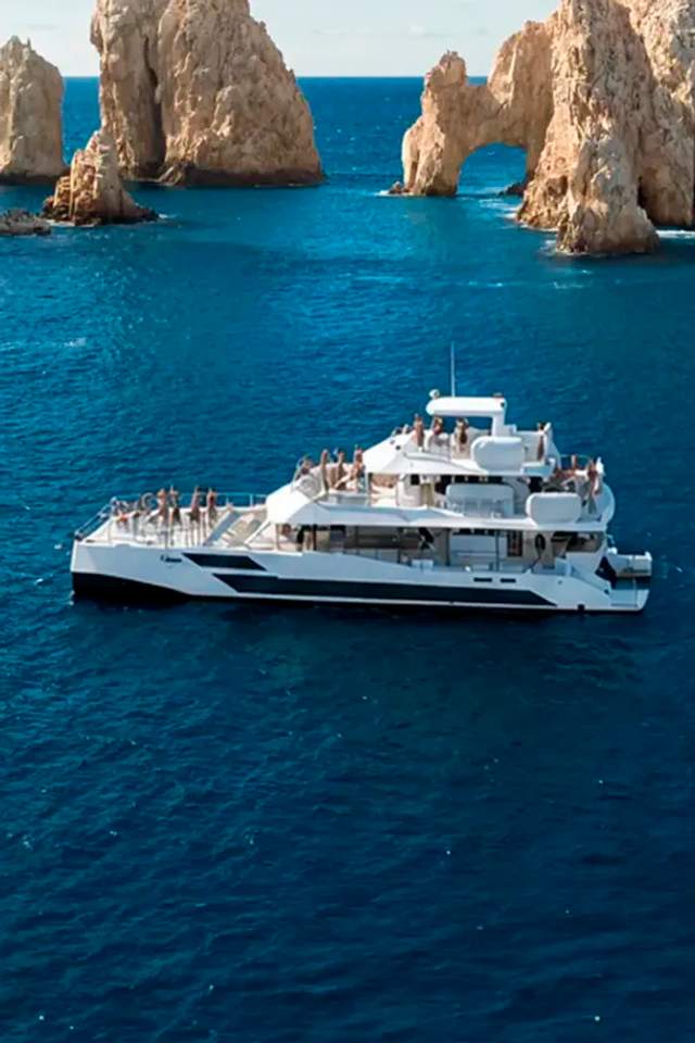 TwentyFive premium 100-ft catamaran sailing in Cabo San Lucas, triple-deck design, open sea views and luxury day cruise.