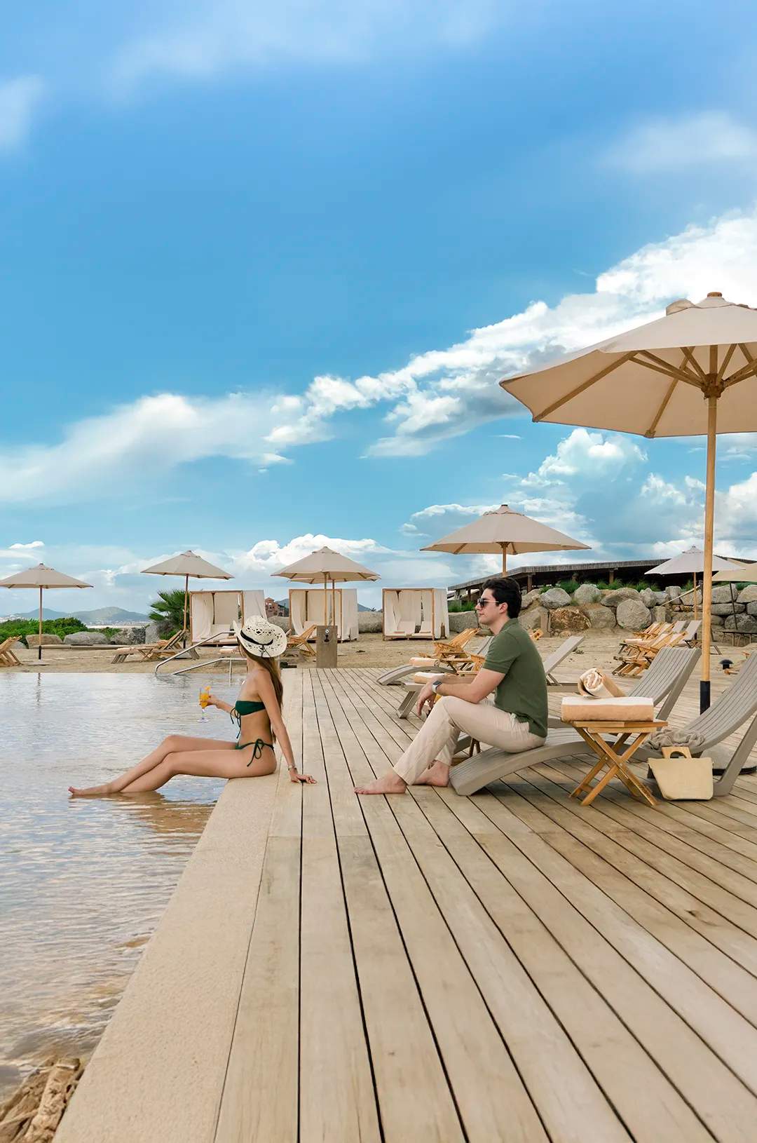 Couple relaxing by the pool with umbrellas at Tierra Sagrada Beach Club in Cabo San Lucas