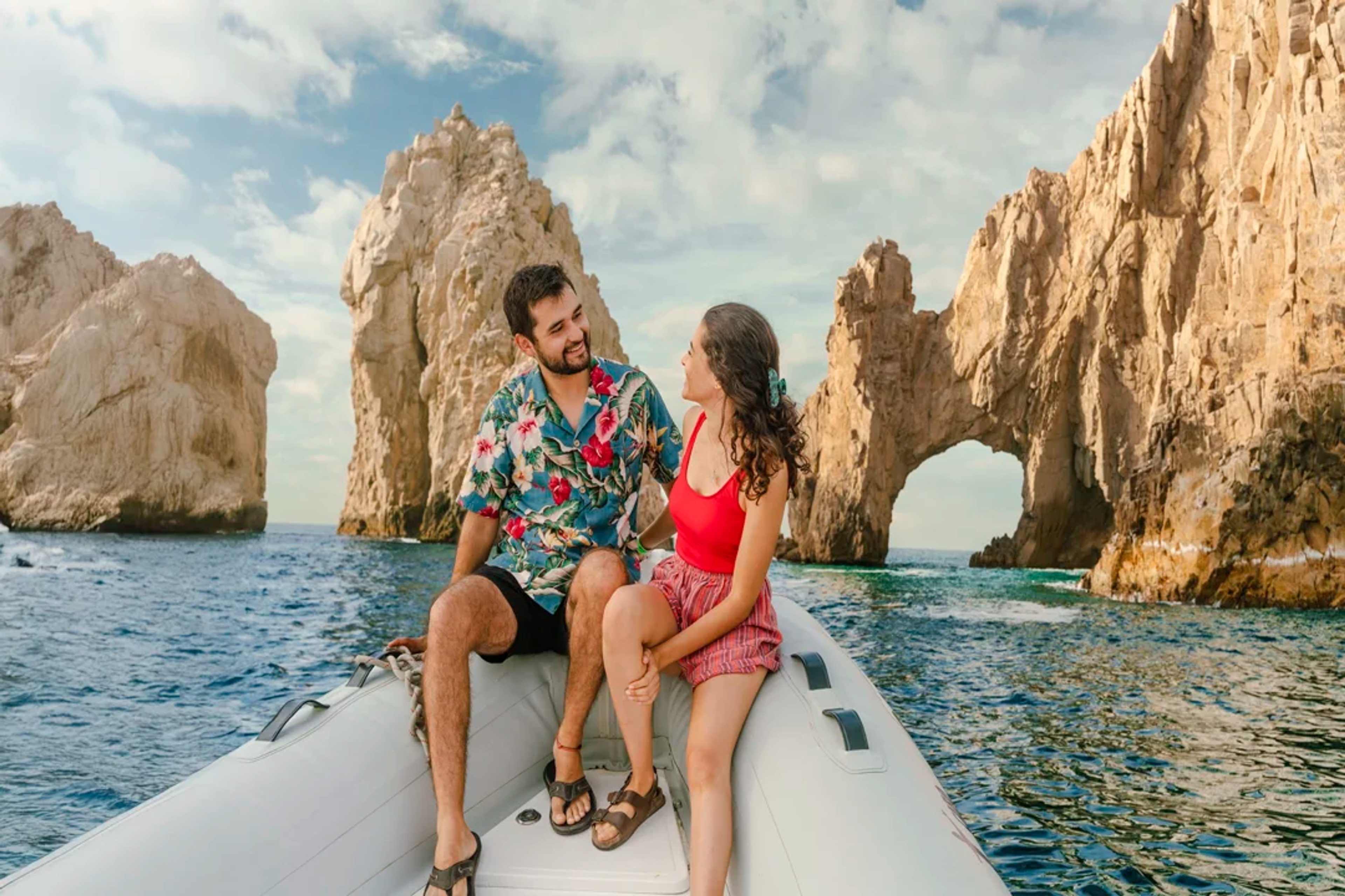 Pareja disfruta un paseo romántico en bote en Cabo, con El Arco como fondo espectacular.