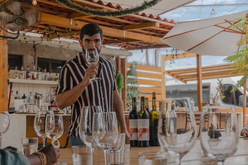 Man at a wine tasting on a terrace, surrounded by glasses and bottles in a relaxed setting.