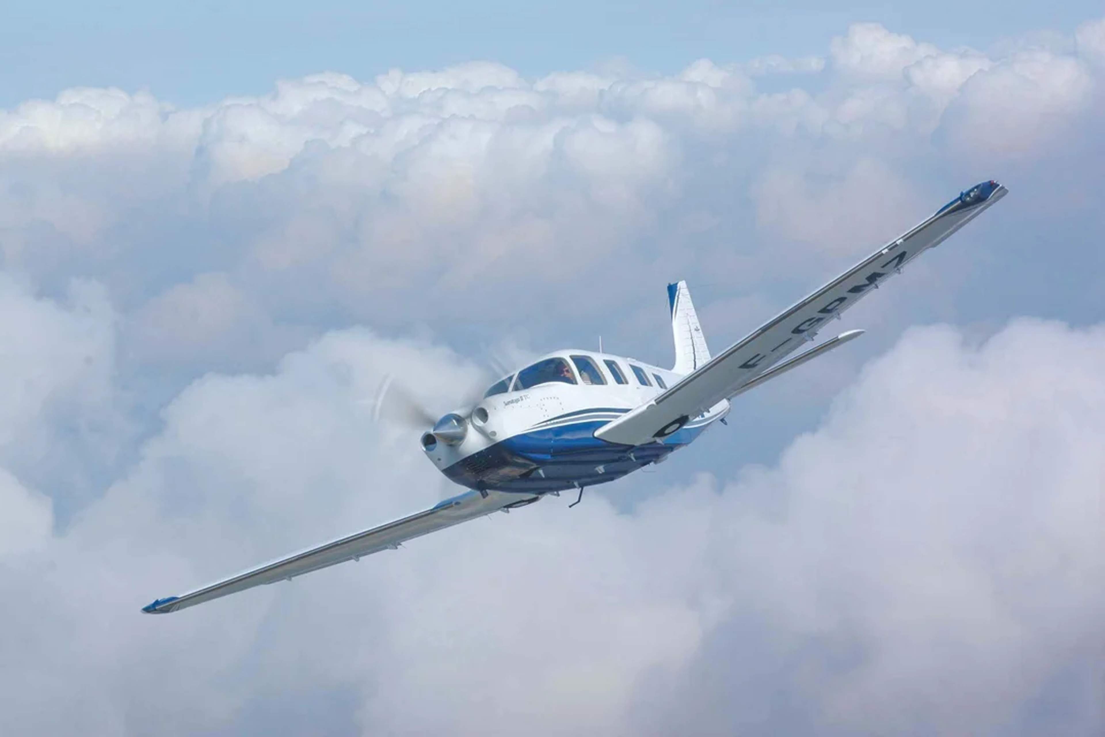 Jet privado volando sobre el océano al atardecer, con nubes dramáticas y luz dorada en el cielo.