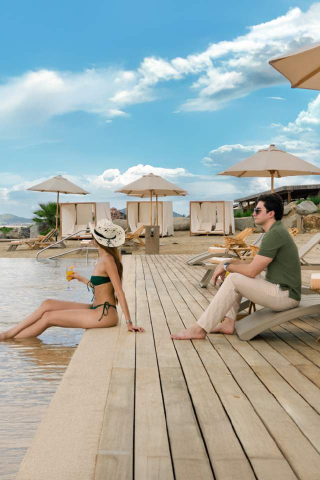Couple relaxing by the pool at Tierra Sagrada Beach Club, Los Cabos, Mexico.