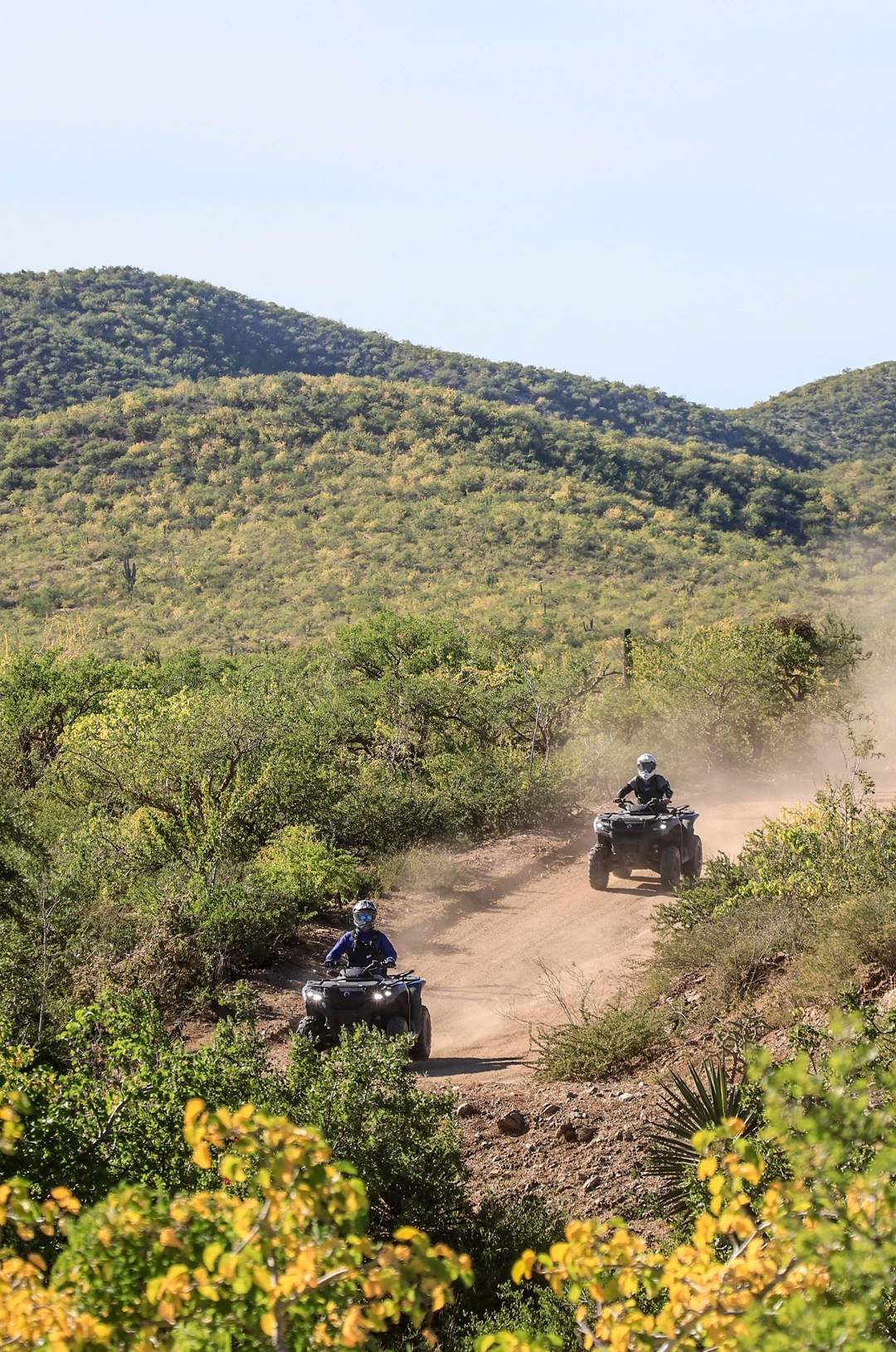 Two off road vehiculos riding on a dusty road
