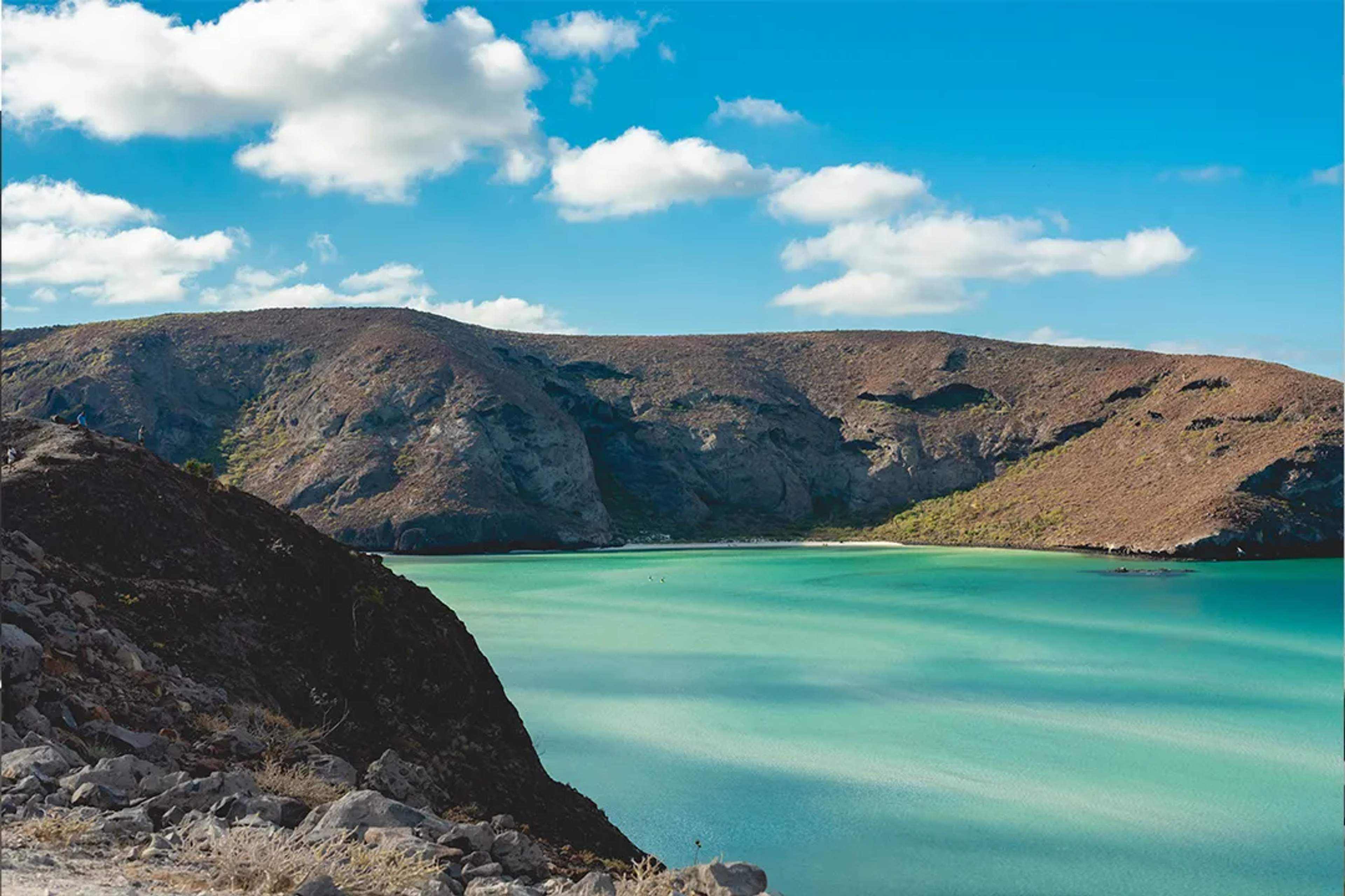 Balandra Beach with turquoise waters and rocky hills under a clear blue sky.