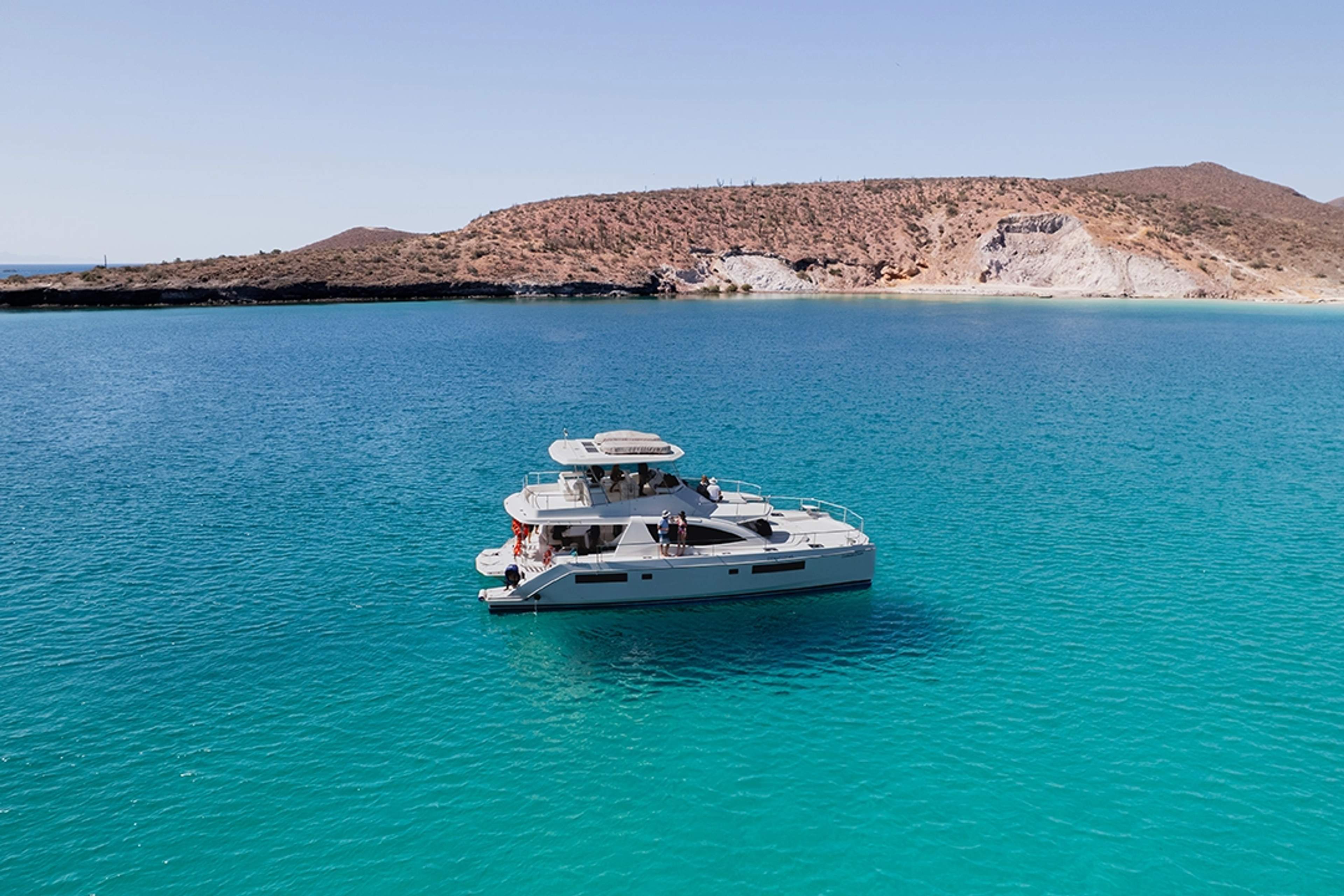 Catamaran floating on the turquoise waters of the Sea of Cortez, surrounded by a serene and arid landscape.