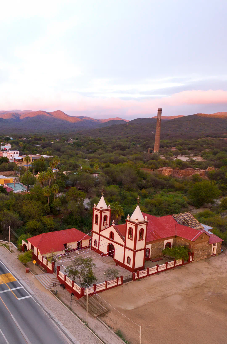 Vista aérea de El Triunfo, Baja California Sur, con su iglesia histórica, la chimenea La Ramona y paisajes montañosos.