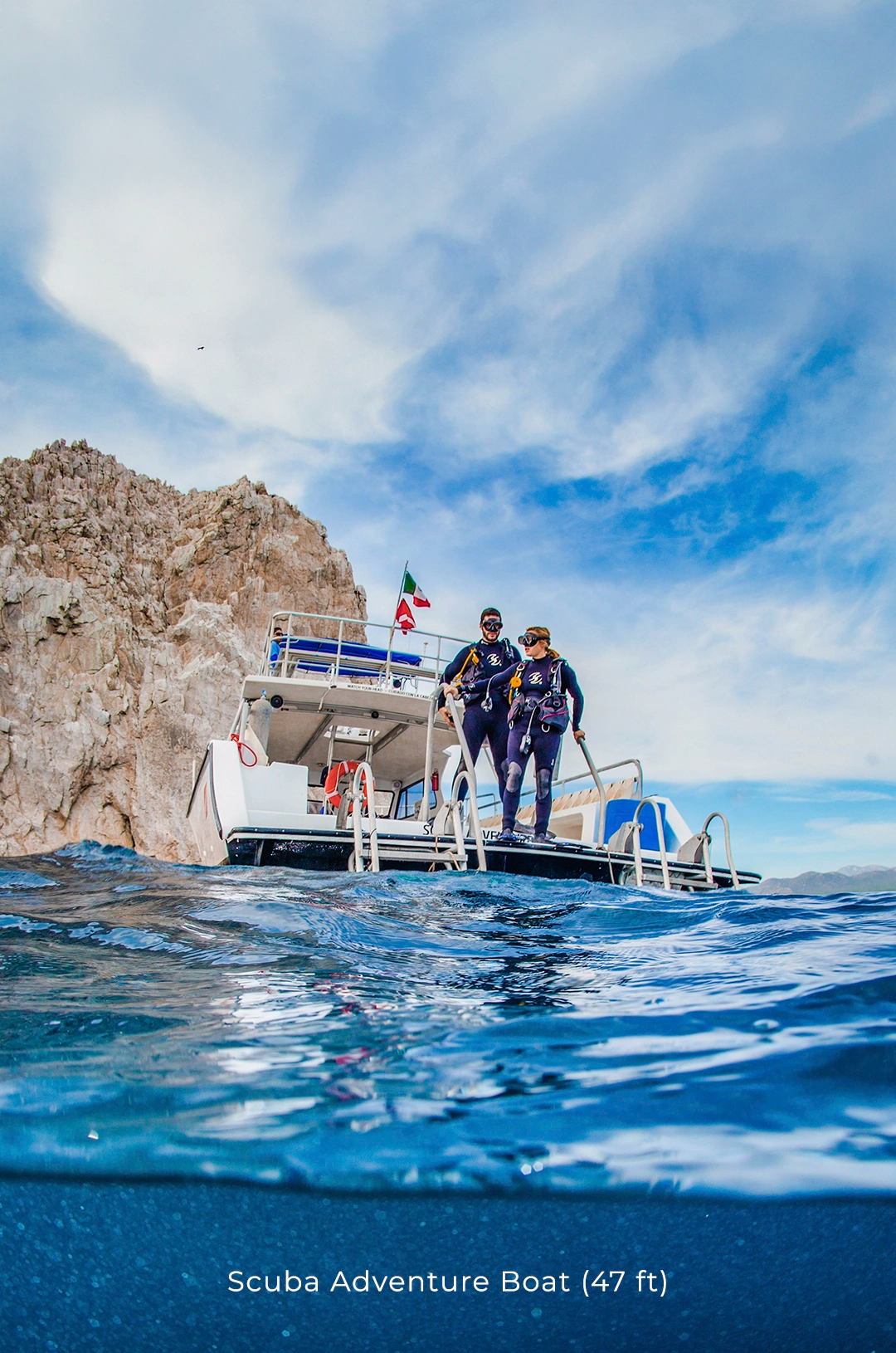 Divers ready to dive from a private boat, surrounded by rocky formations in Cabo San Lucas.