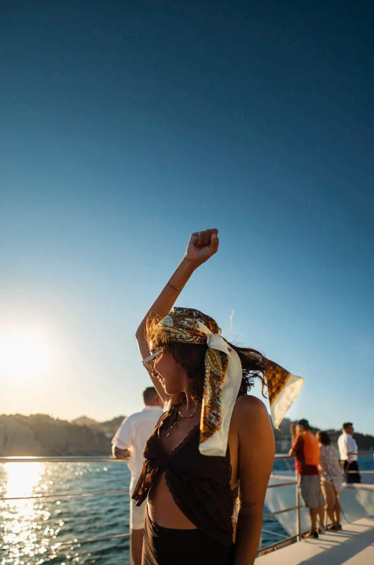Woman dancing and enjoying the sunset aboard the Oceanus catamaran in Los Cabos.