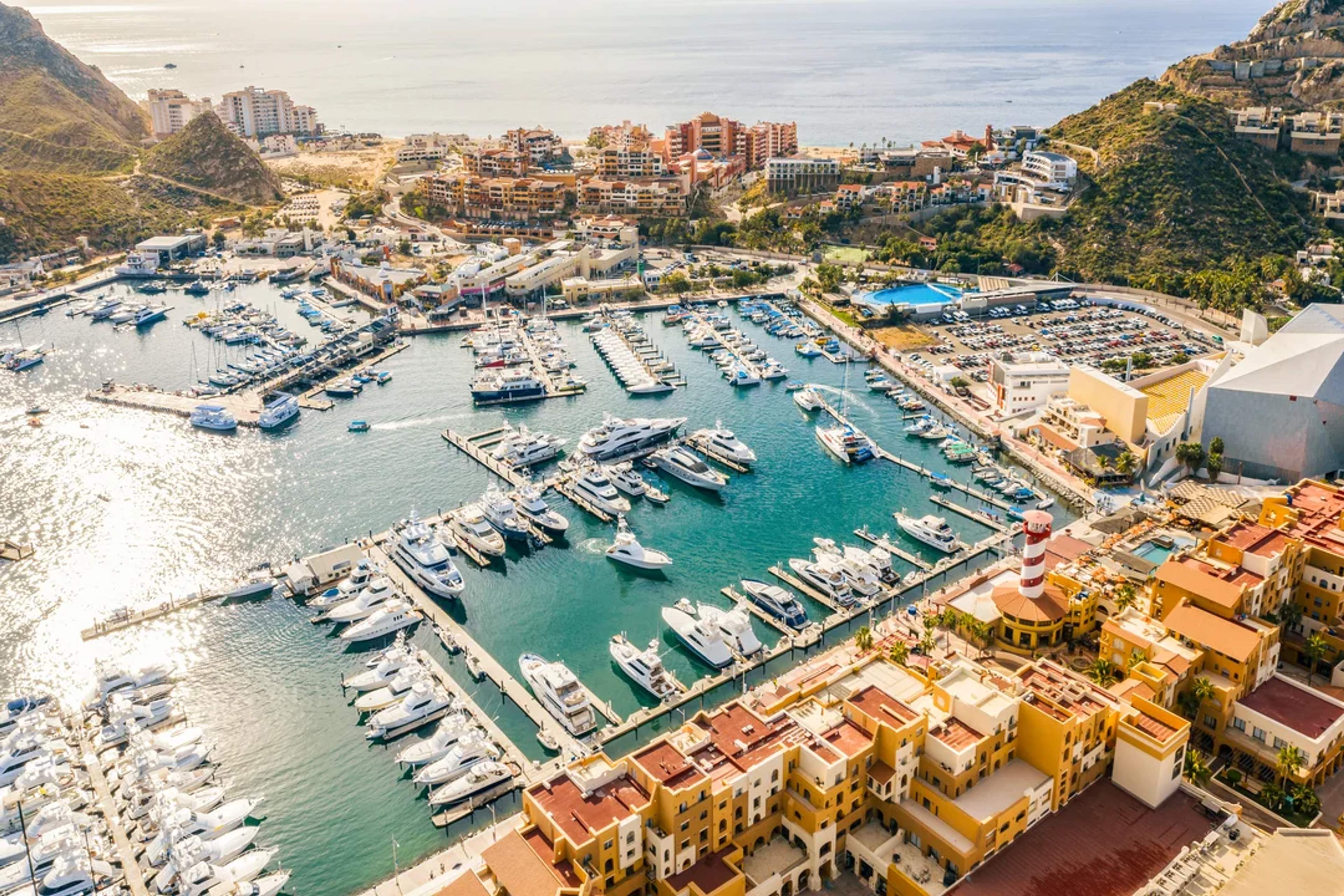 Vista aérea de la Marina de Cabo San Lucas, con yates, resorts y montañas costeras escénicas.