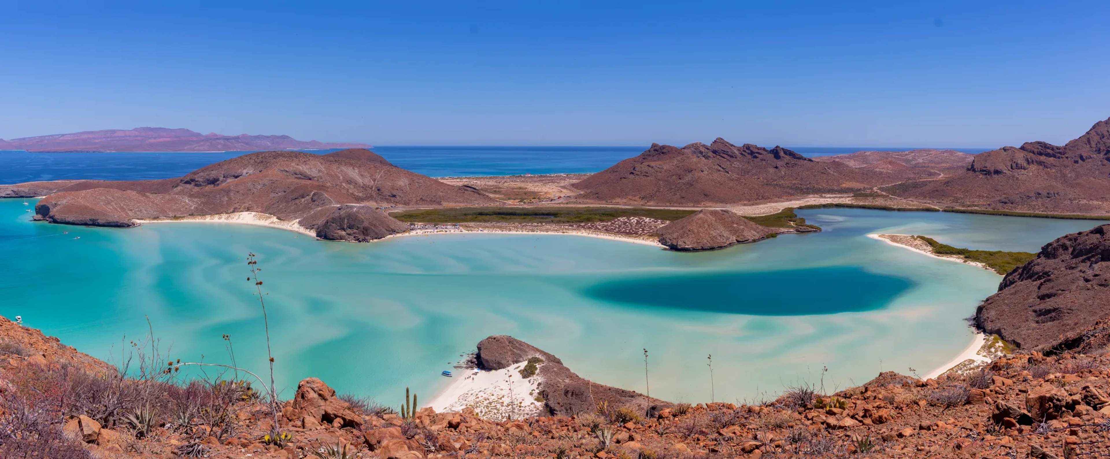 Aerial view of Balandra Beach's pristine turquoise lagoon framed by volcanic rock and desert landscape near La Paz, Baja