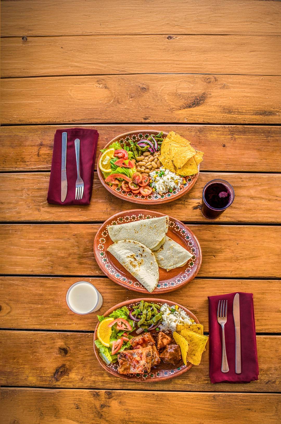 Traditional Mexican dishes served on colorful clay plates over a rustic wooden table.