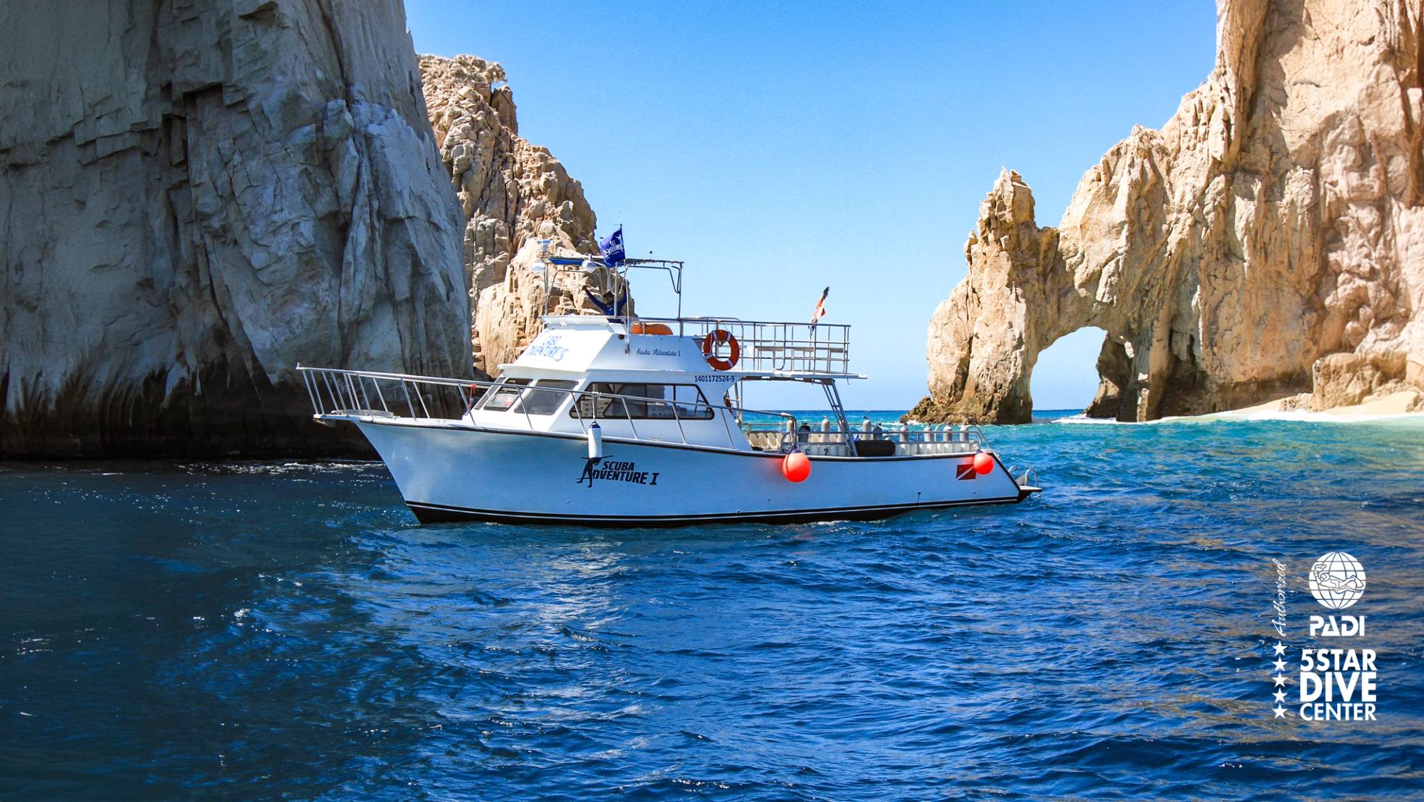 The boat "Scuba Adventure I" floats near cliffs and the iconic rock ...