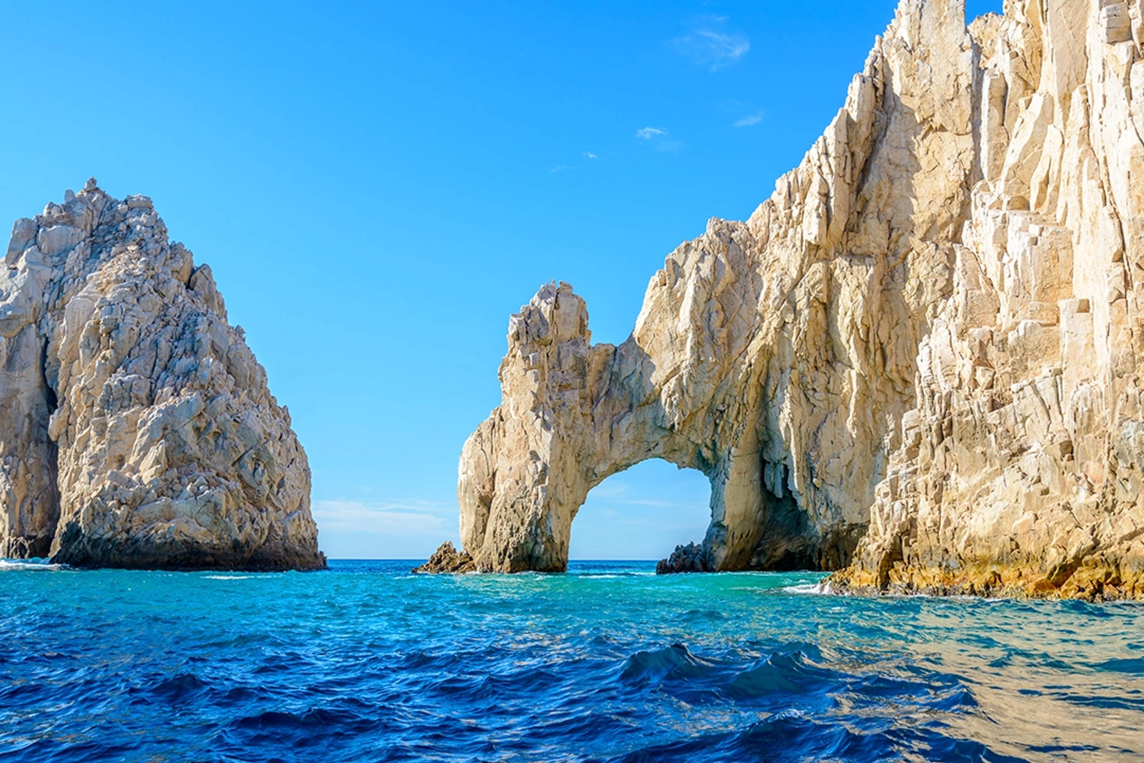 El icónico Arco de Cabo San Lucas (El Arco) se eleva sobre el océano azul bajo un cielo claro y brillante en Baja California.
