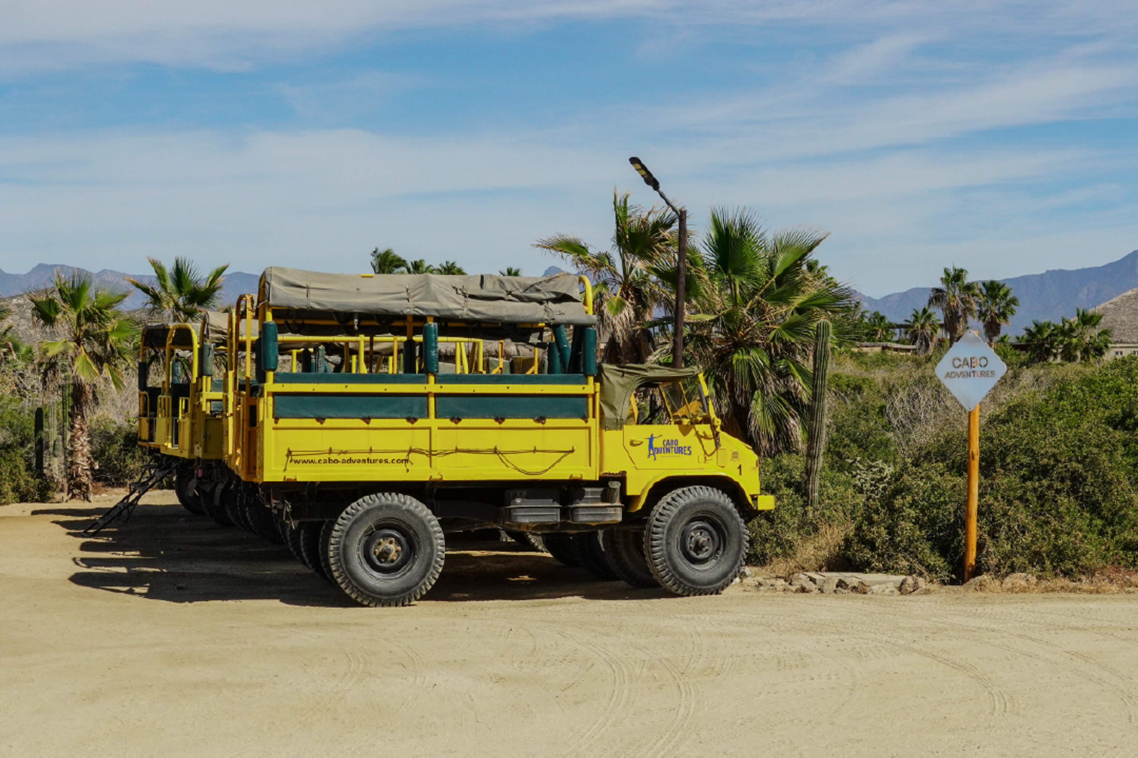 Yellow Cabo Adventures Unimog truck parked in desert landscape at Tierra Sagrada, Cabo San Lucas