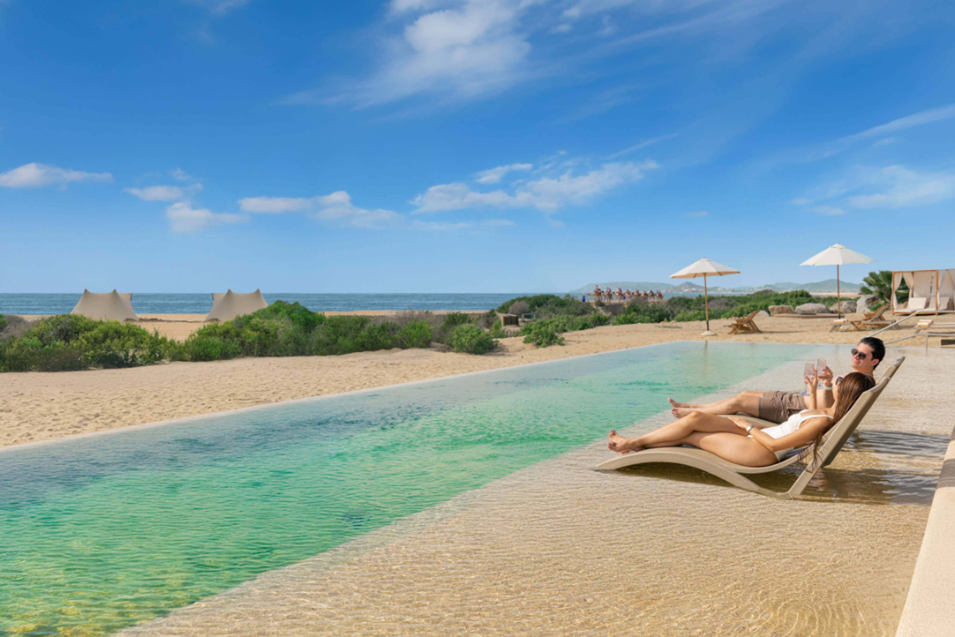 Adults enjoy by the pool at Tierra Sagrada Beach Club by Cabo Adventures.