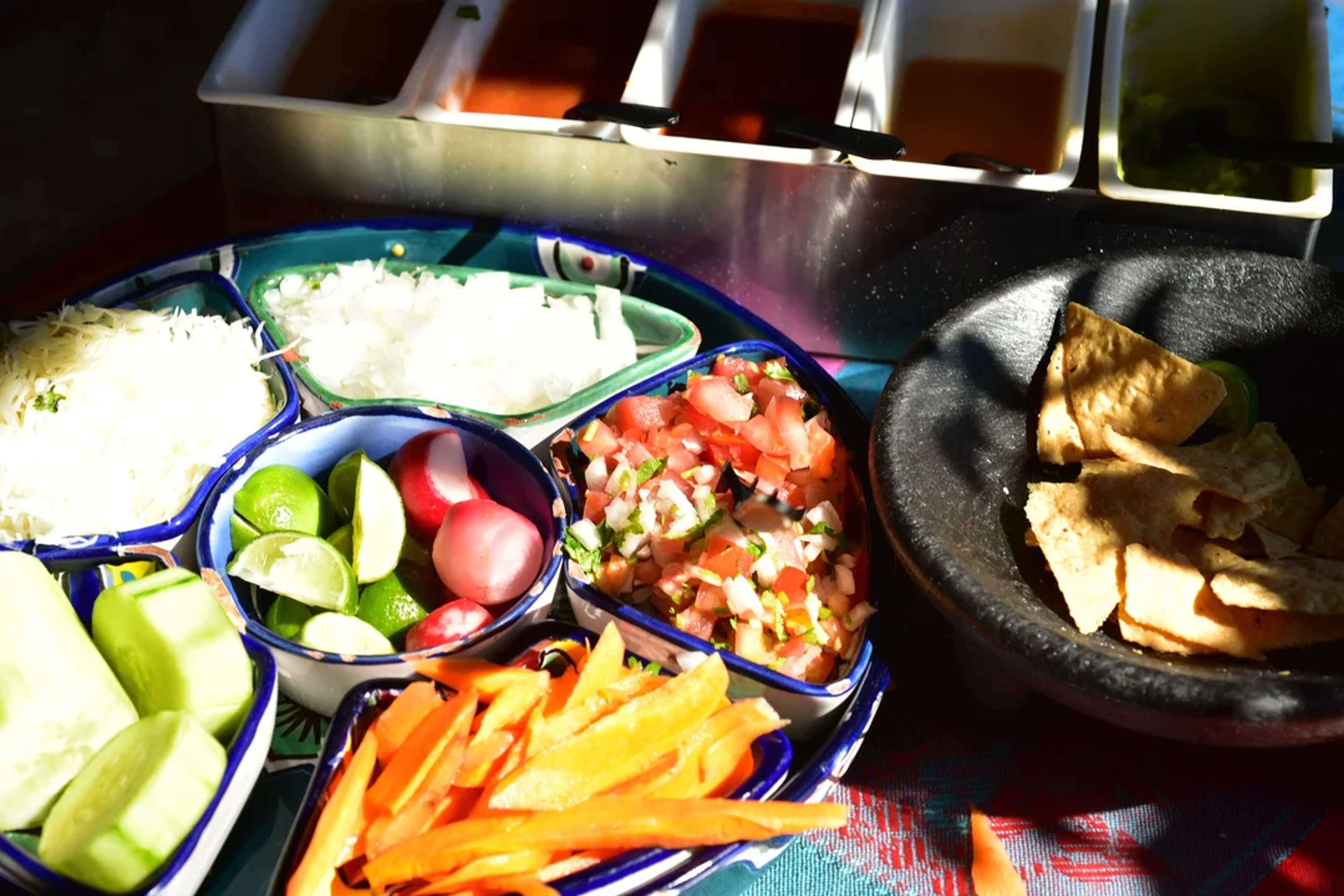 Un colorido platillo mexicano con salsa fresca, limón, rábanos y totopos, ideal para una auténtica fiesta gastronómica.