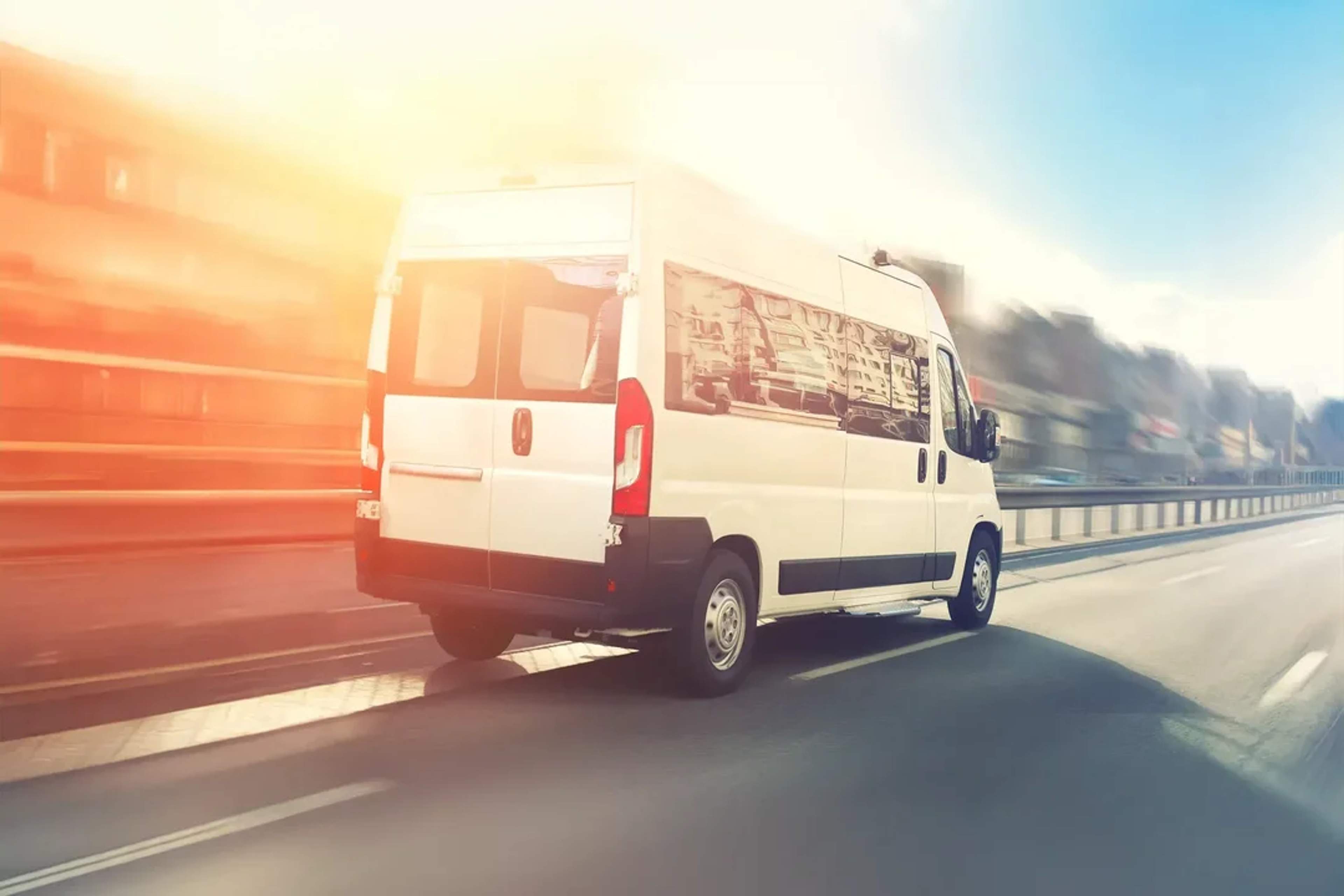 Camioneta blanca de pasajeros en carretera al amanecer, ideal para traslados al hotel o aeropuerto.