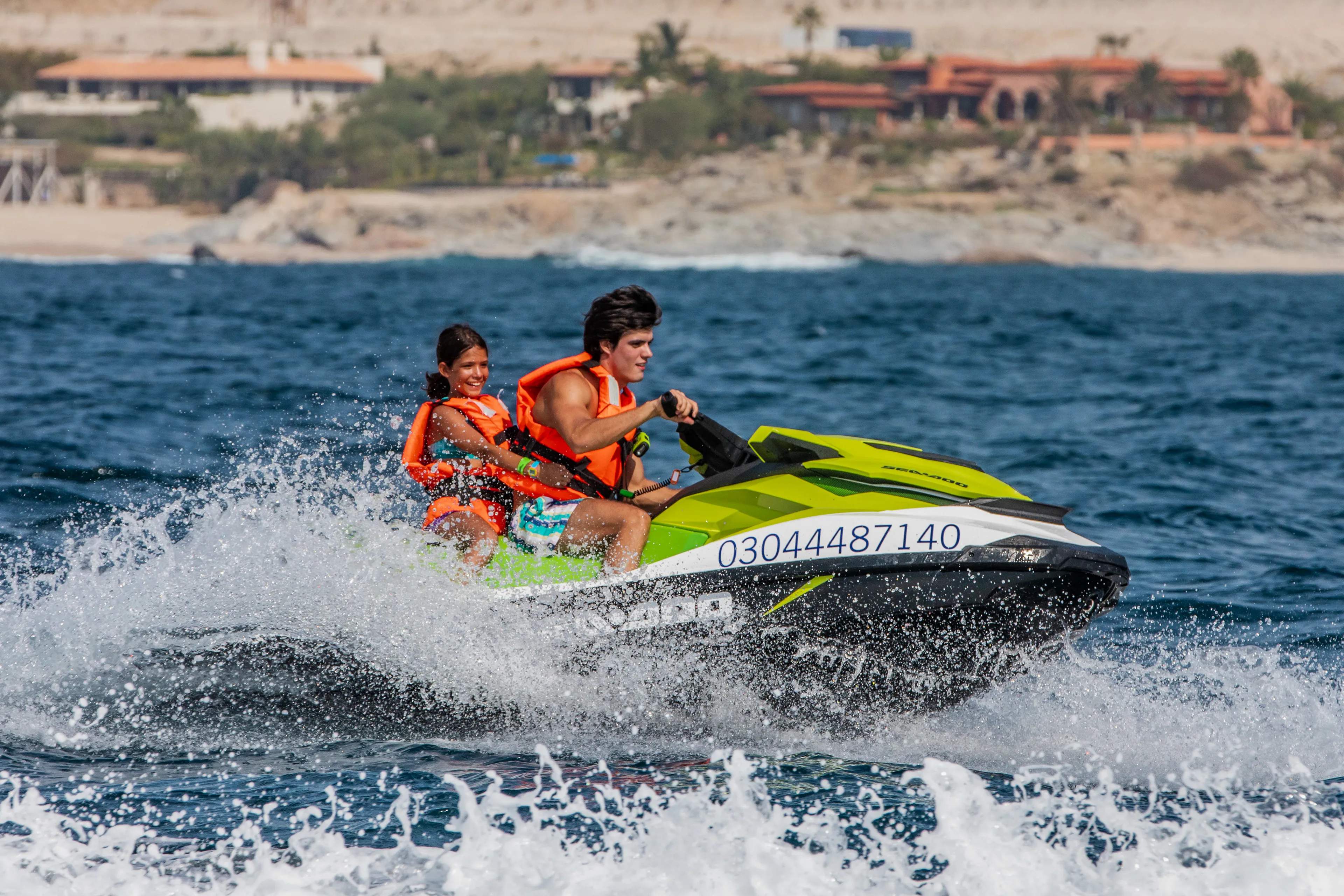 Adult and child riding a Jet Ski with Cabo Adventures along the coast of Los Cabos.