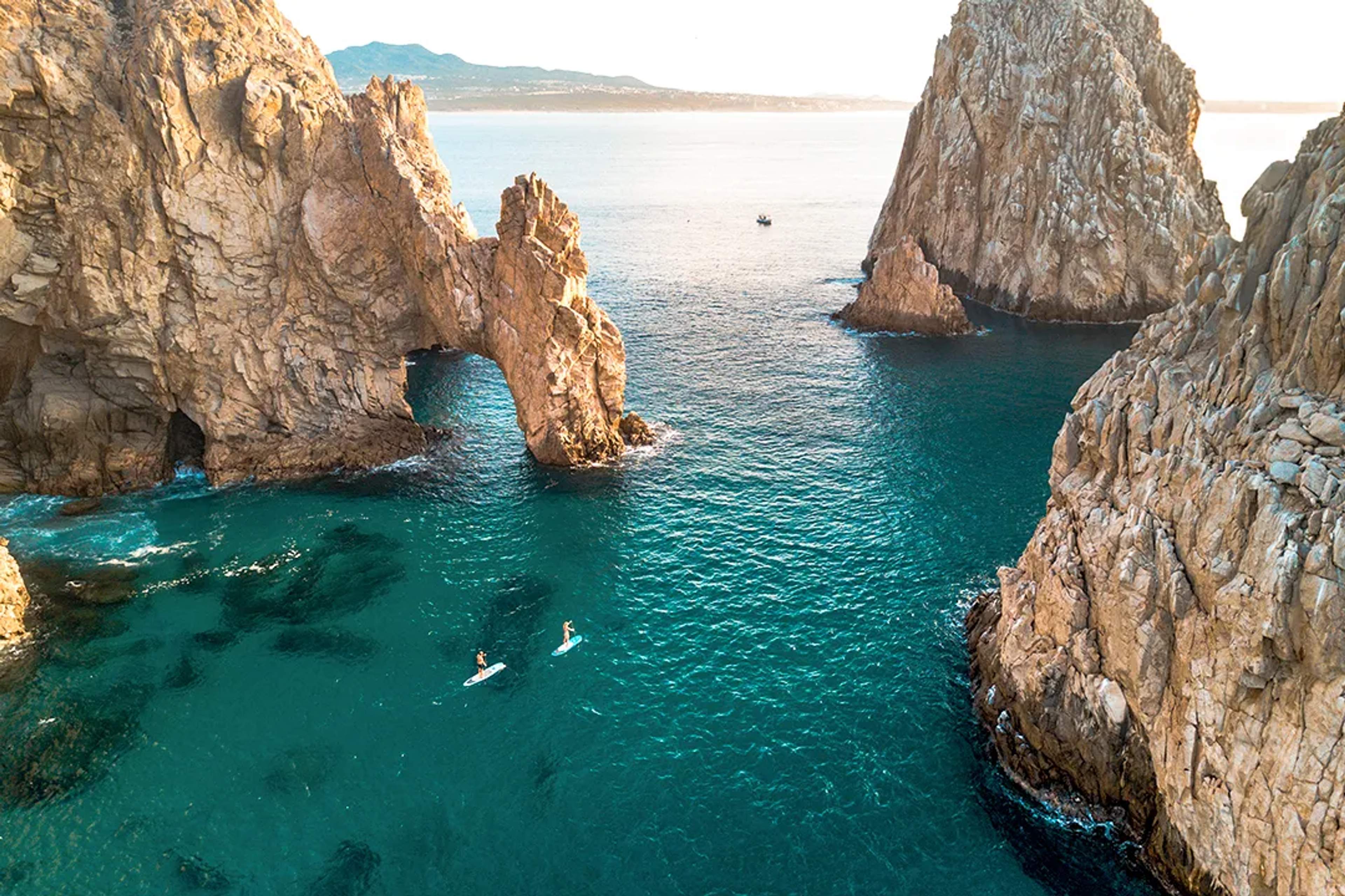 Paddleboard bajo El Arco en un tour de snorkel y kayak en Los Cabos, Cabo San Lucas