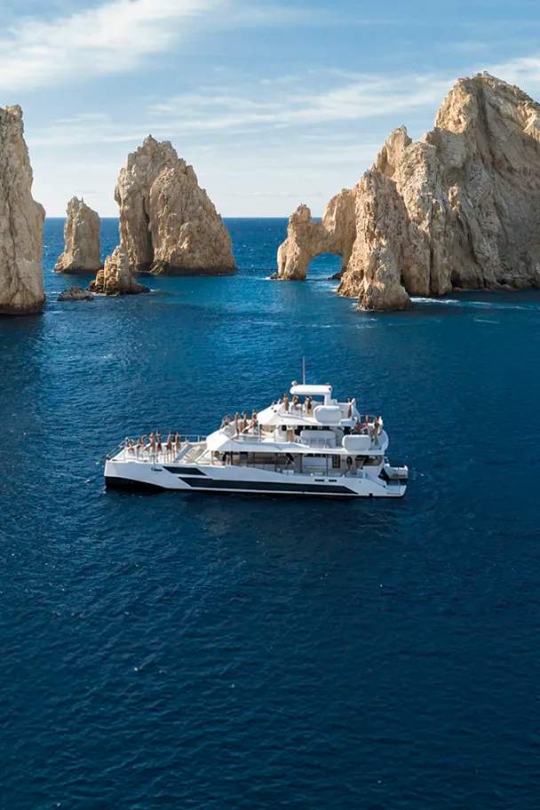TwentyFive premium 100-ft catamaran sailing in Cabo San Lucas, triple-deck design, open sea views and luxury day cruise.