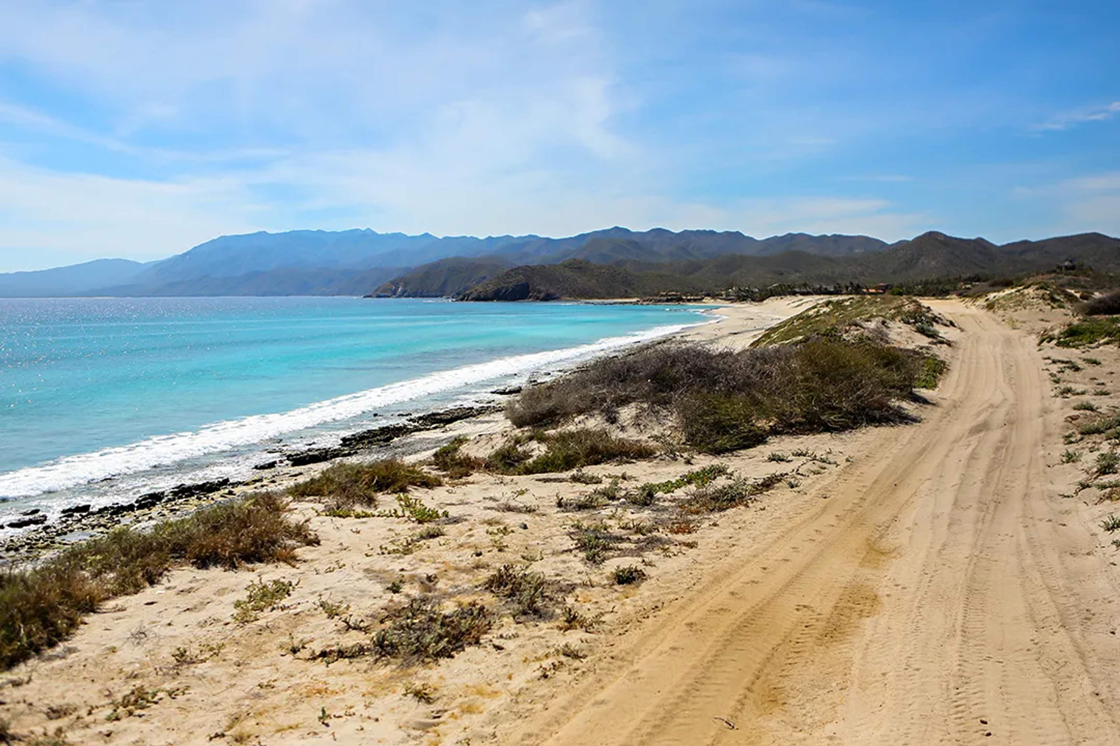 Playa remota en East Cape con aguas turquesa del Mar de Cortés, arena dorada y montañas desérticas