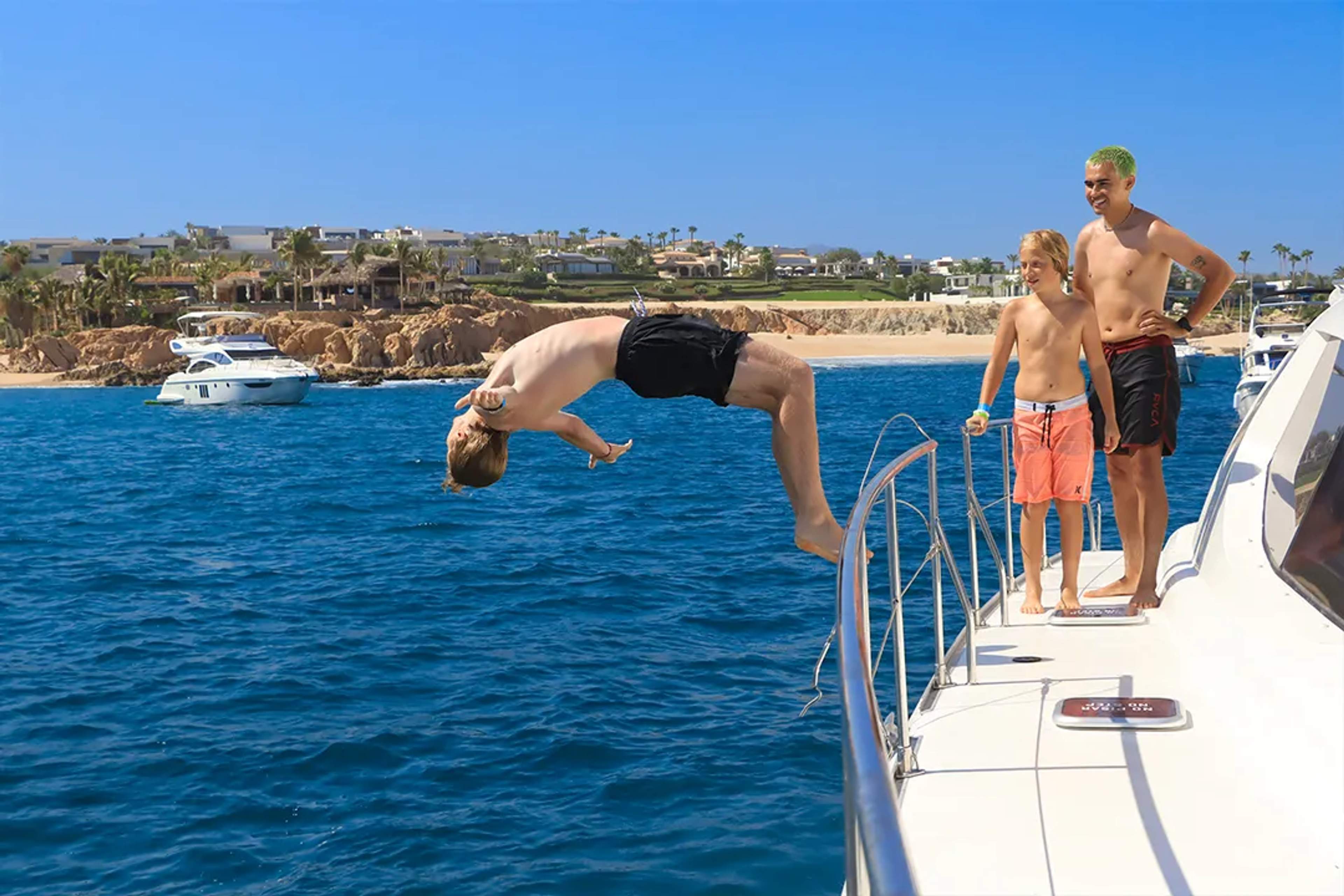 Guest backflips into the sea from a yacht during the Two Bay Tour in Cabo with family onboard