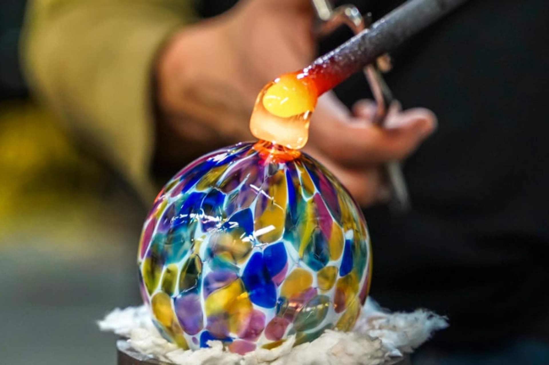 A close-up of a colorful glass orb being shaped by a glassblower in Cabo, showcasing the intricate art of glassblowing.