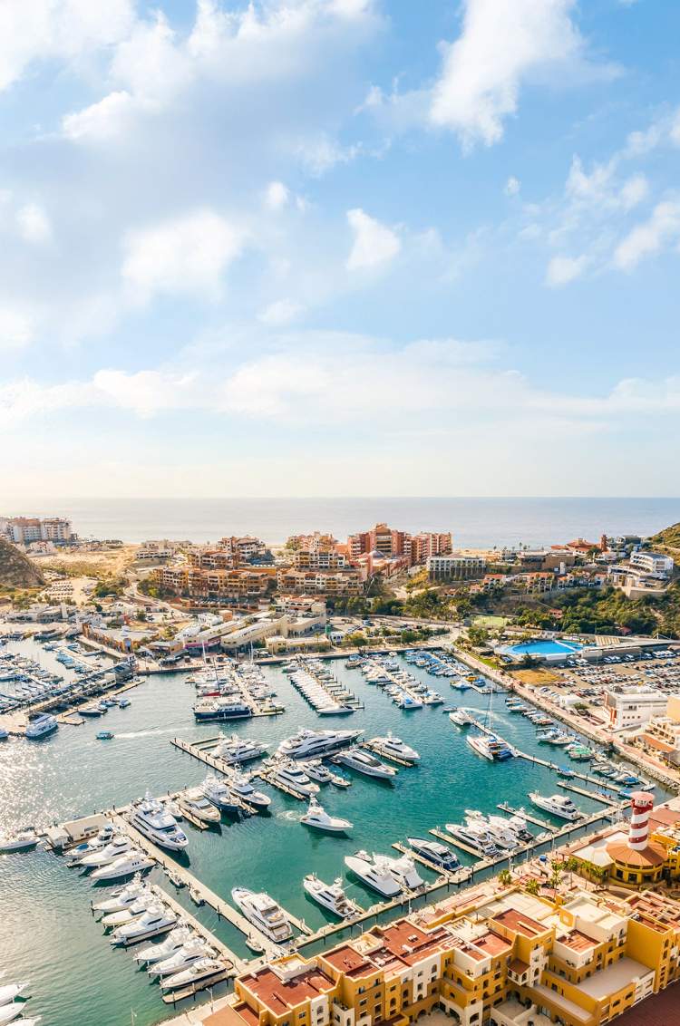 Impresionante vista aérea de la Marina de Cabo San Lucas, con yates de lujo y rodeada de colinas.