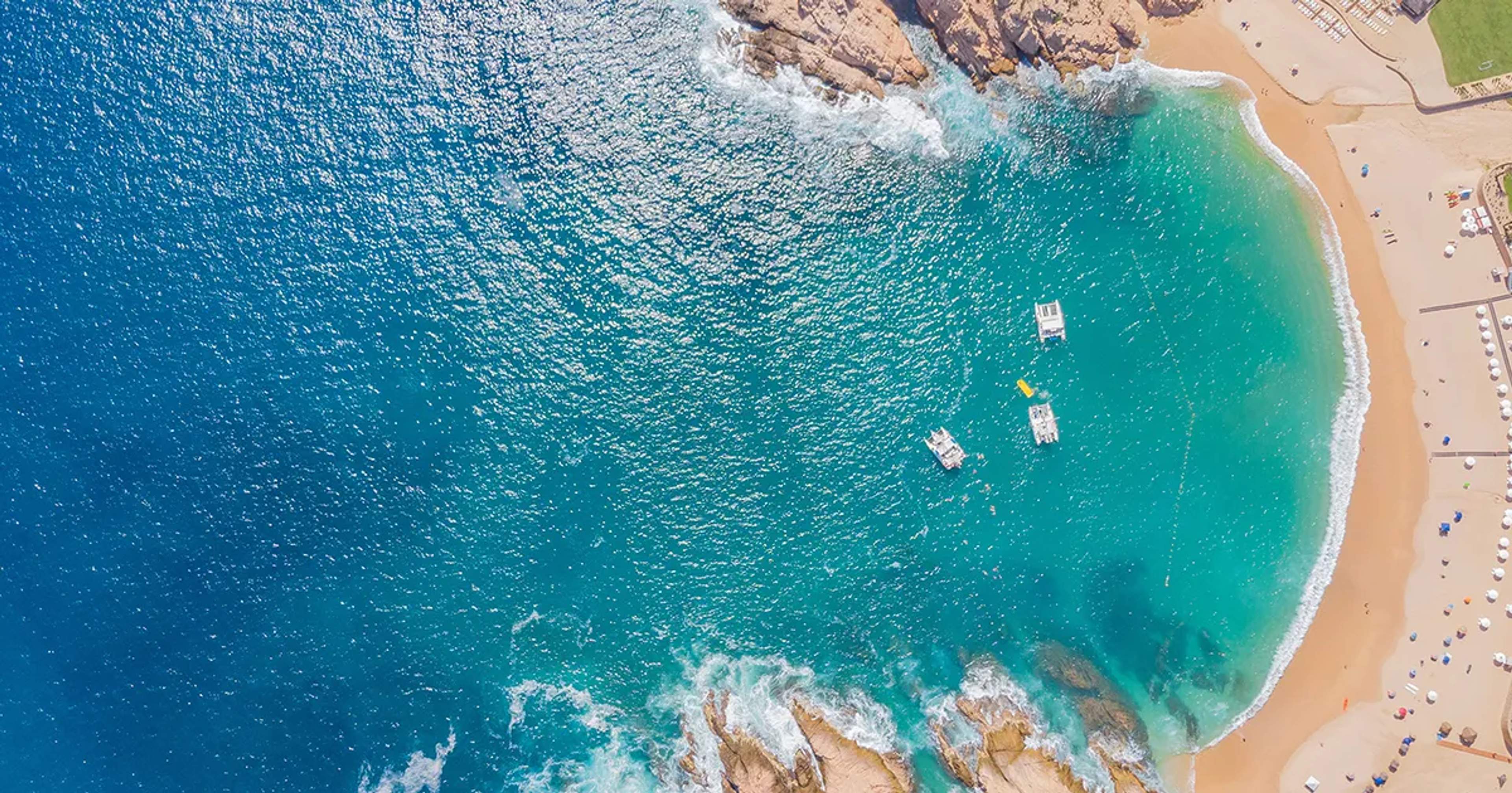 Aerial view of Cabo San Lucas beach with turquoise Sea of Cortez and boats near rocky coastline