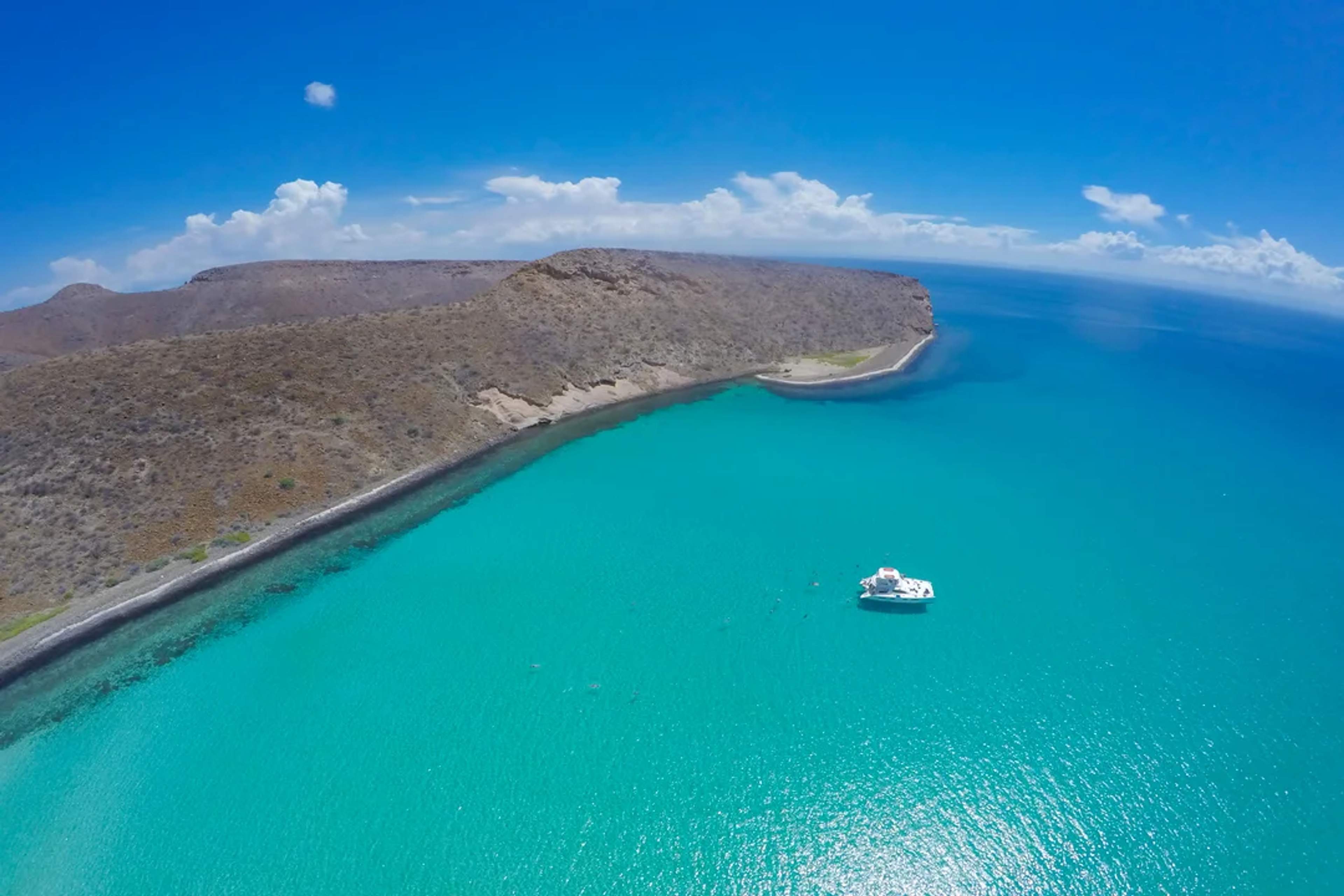 A white yacht floats in turquoise waters near Balandra's stunning desert coastline.
