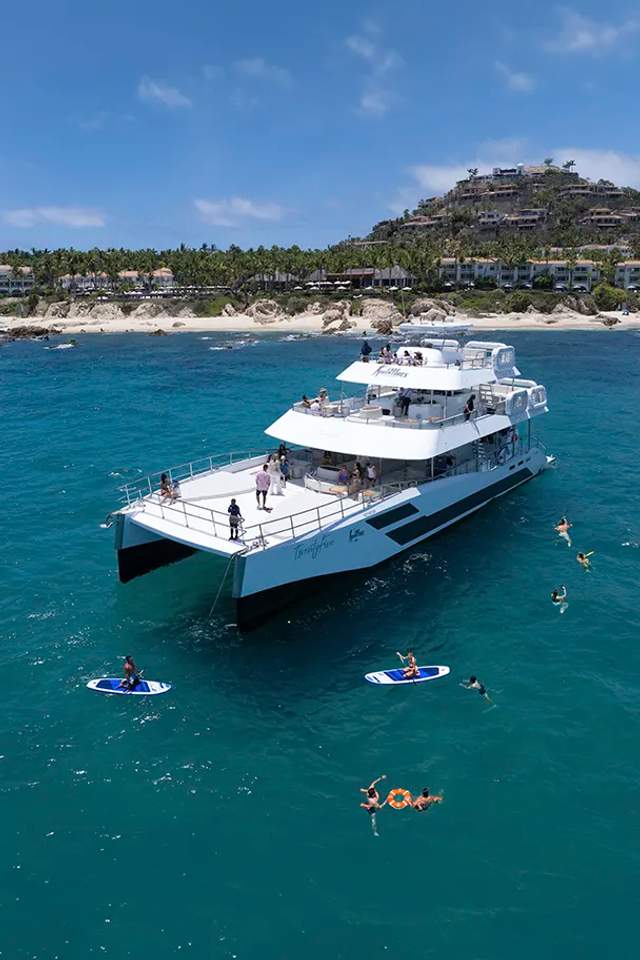 TwentyFive premium 100-ft catamaran sailing in Cabo San Lucas, triple-deck design, open sea views and luxury day cruise.