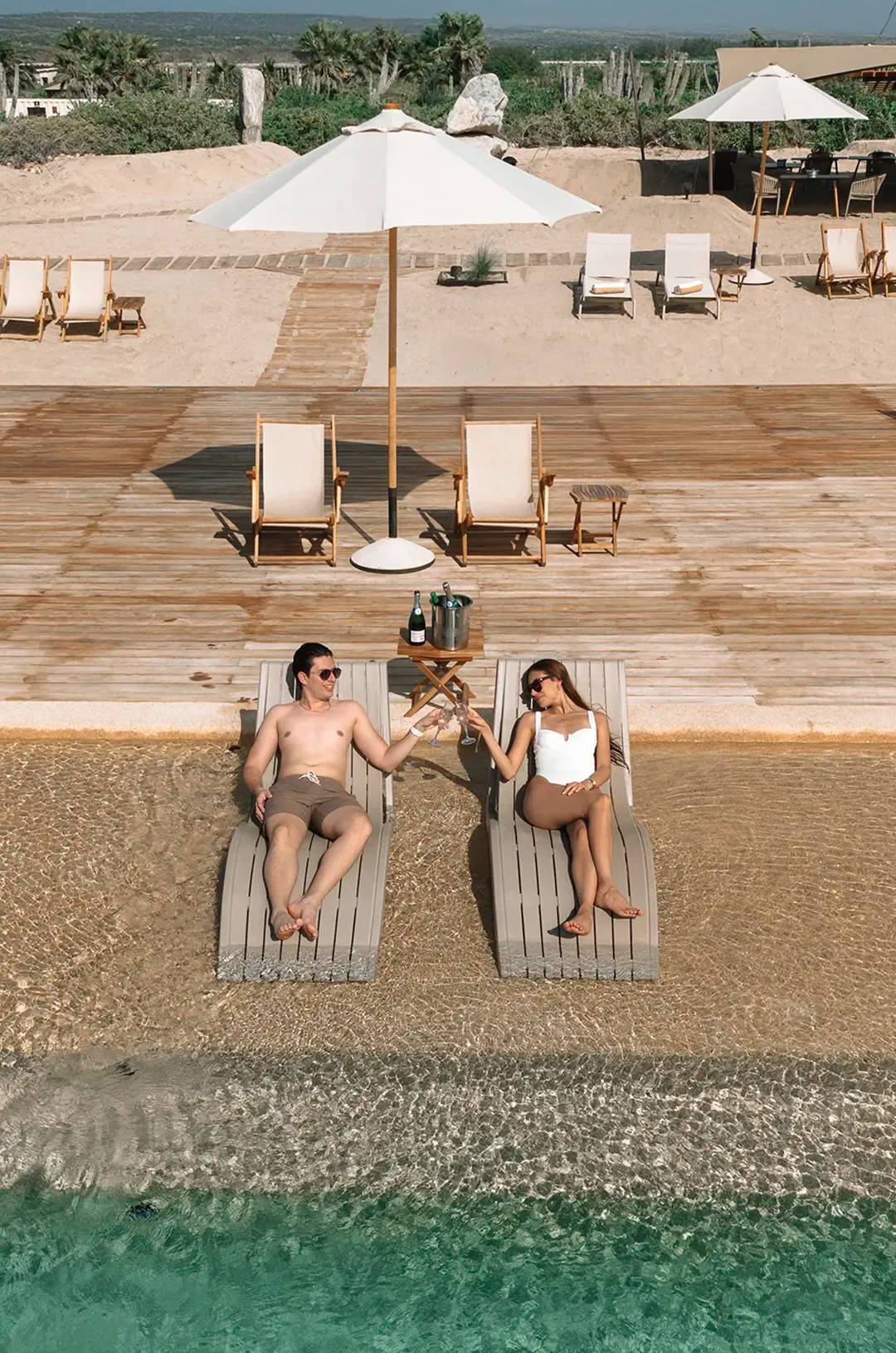 Couple relaxing on loungers with champagne at Tierra Sagrada Beach Club in Cabo San Lucas