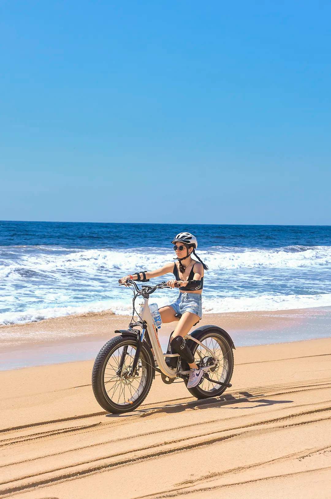 Young lady riding an e-bike along the shoreline at Tierra Sagrada Beach & Adventure Park