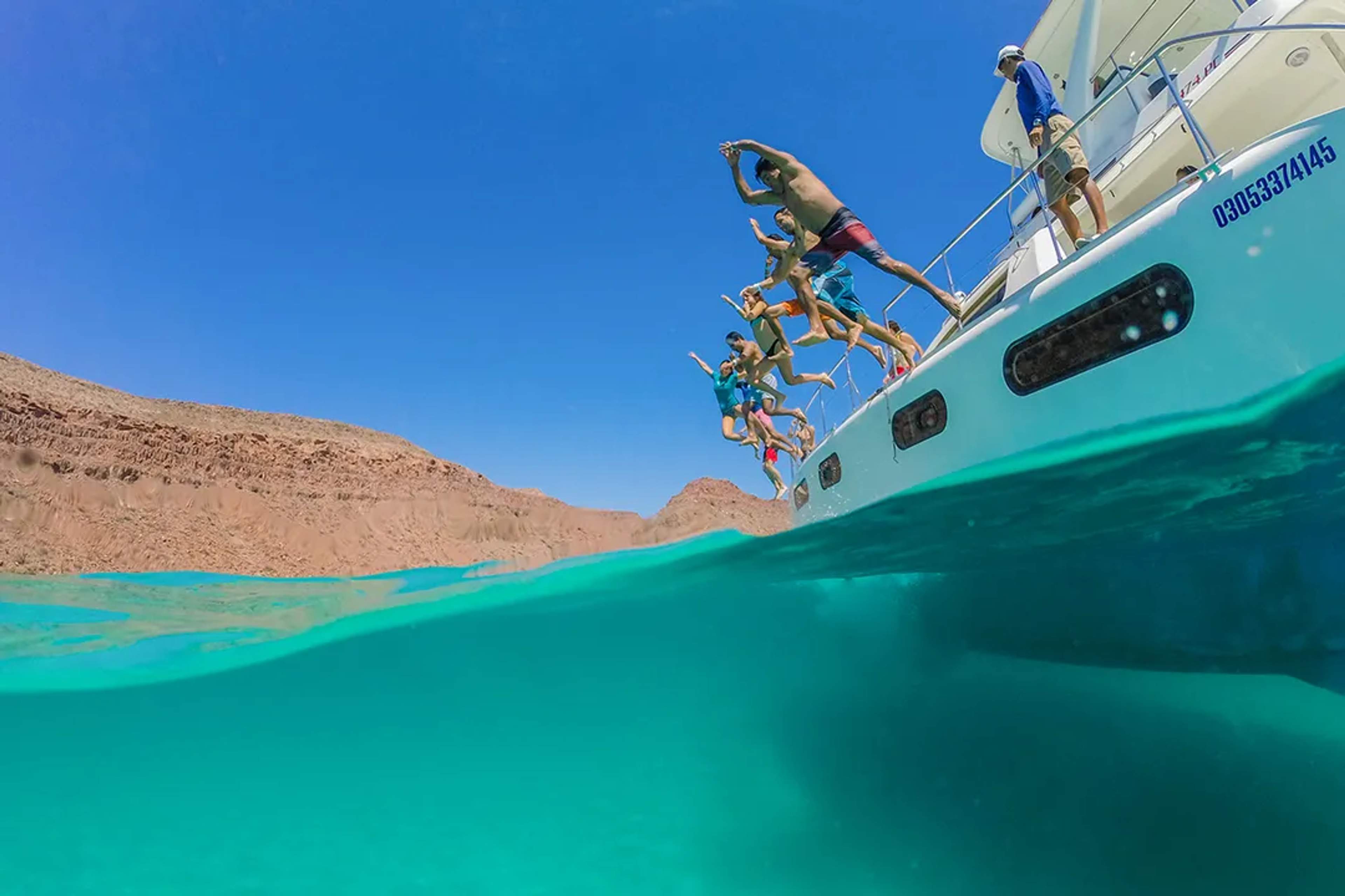 Guests jumping from a boat into turquoise water during a guided ocean adventure in Baja Mexico